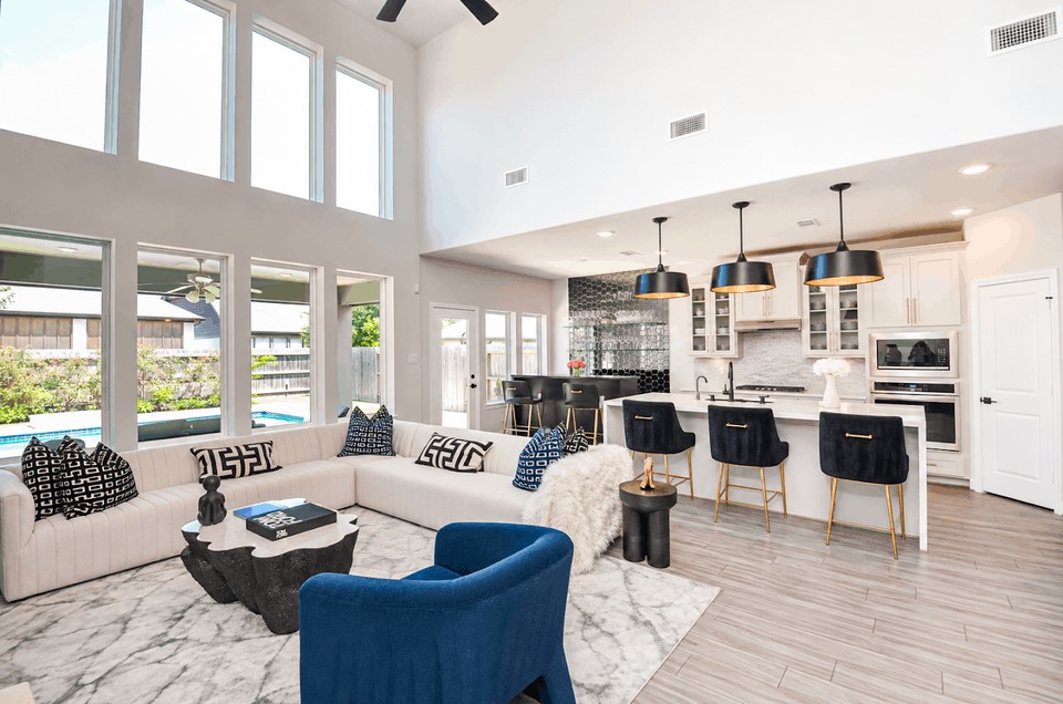Stunning open-concept living space with soaring ceilings and abundant natural light, featuring a modern kitchen with a chic breakfast bar, stylish pendant lighting, and a cozy living area perfect for entertaining.