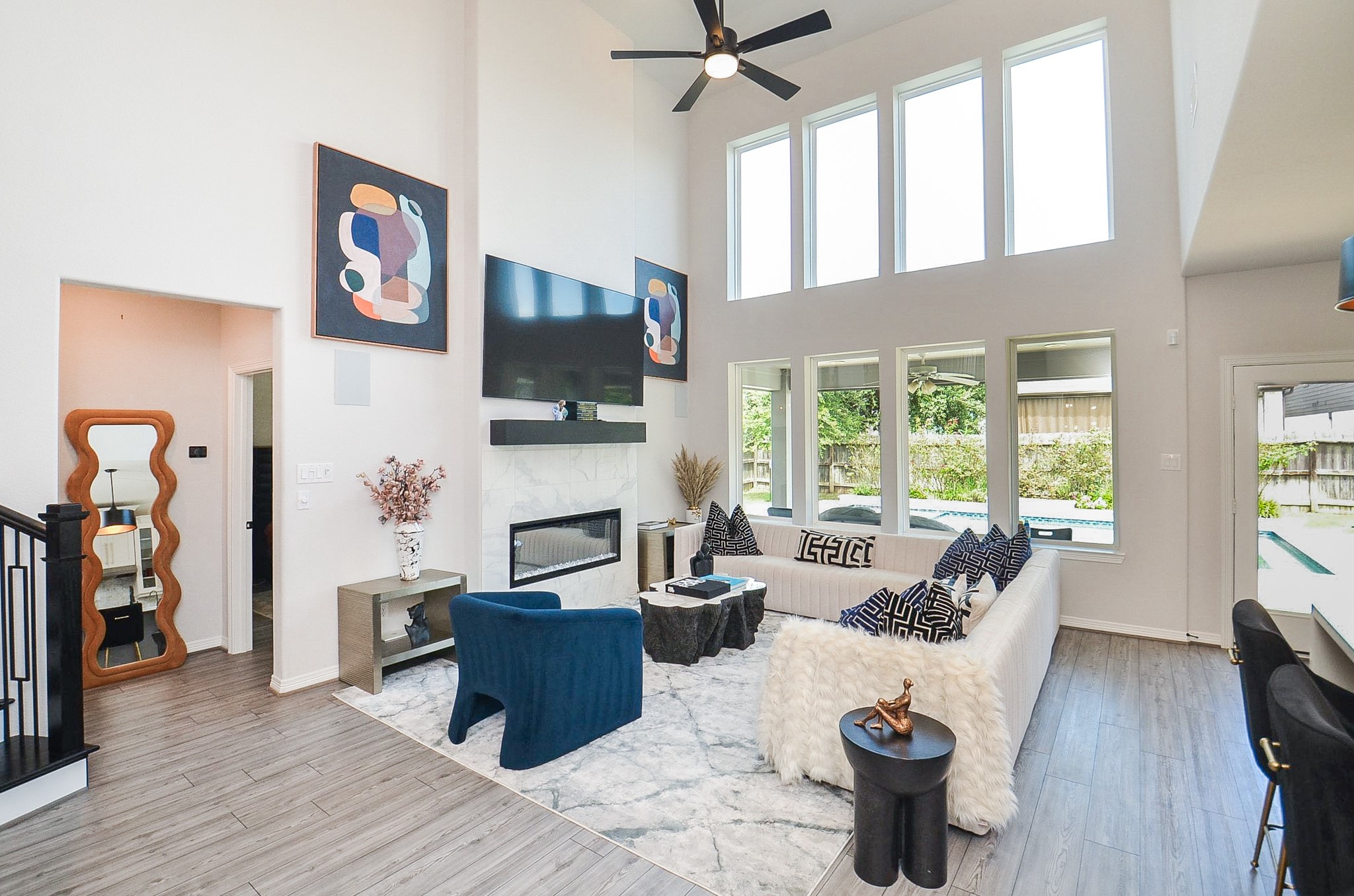 Spacious living room with soaring ceilings, abundant natural light, and a modern fireplace, perfect for entertaining or relaxing.