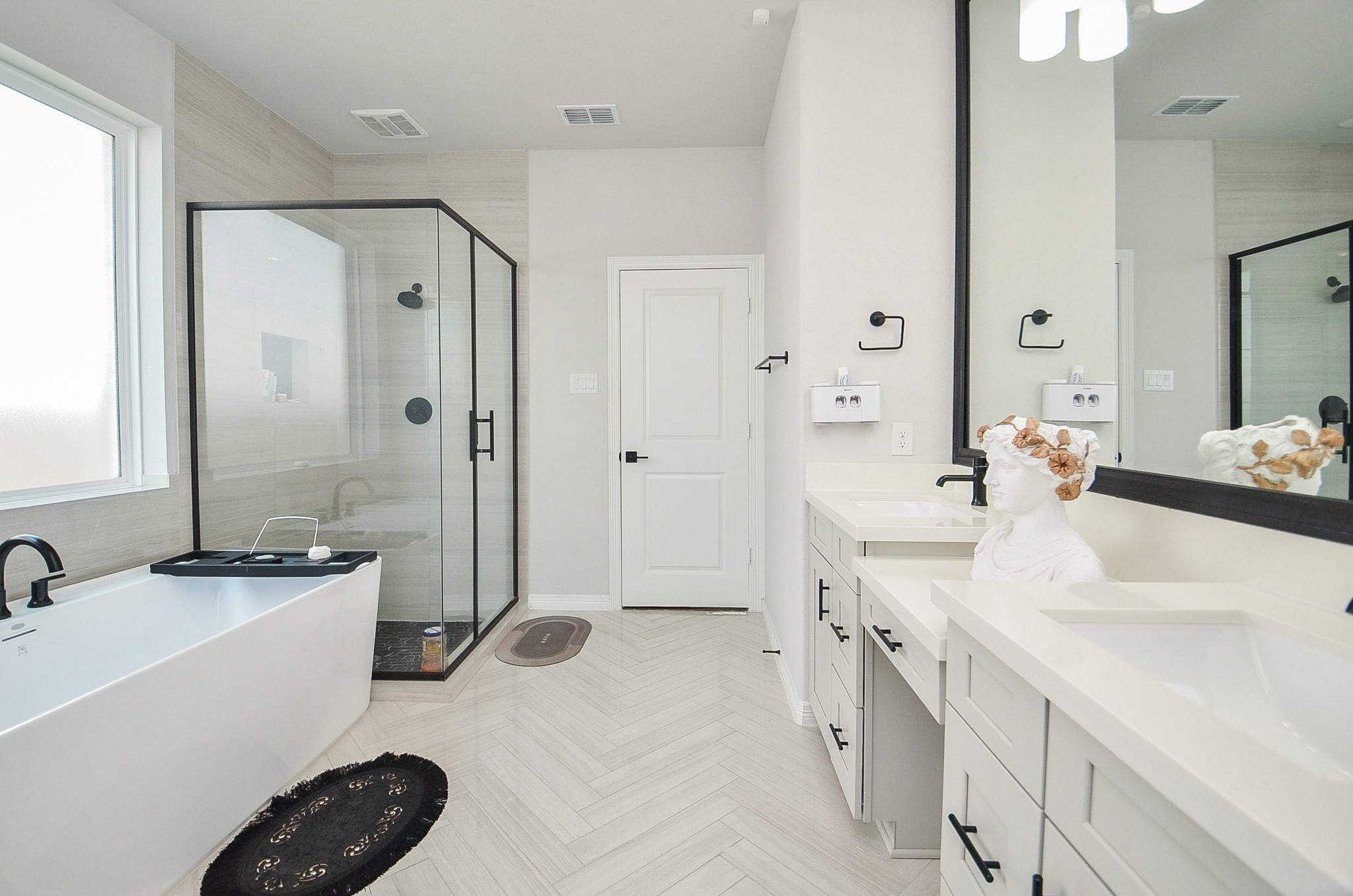 Elegant bathroom featuring a spacious glass-enclosed shower, modern freestanding tub, and dual vanities with sleek fixtures.