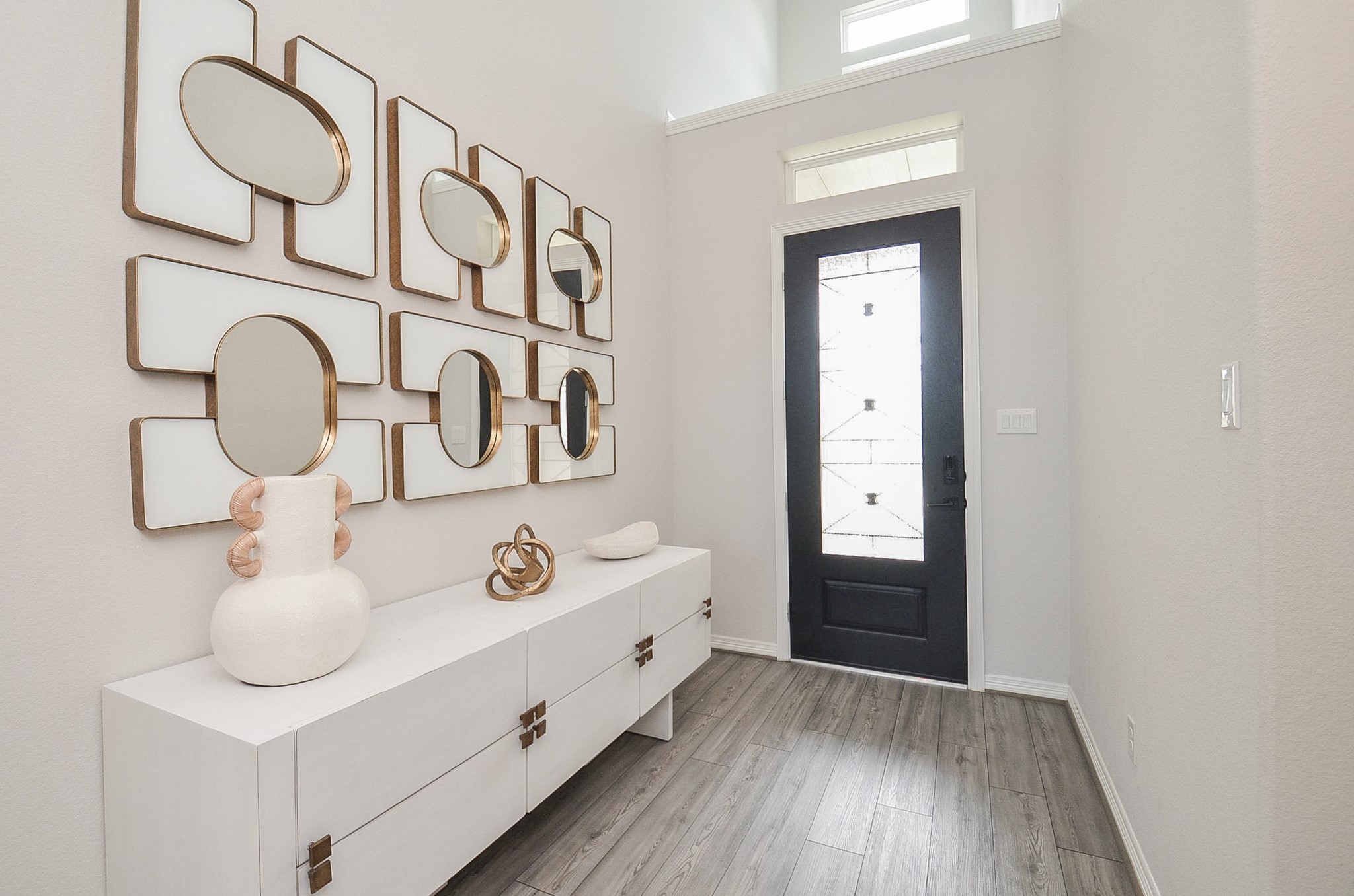 Elegant two-story foyer with a striking modern chandelier, artistic wall accents, and a view of the spacious, sunlit living area below. Elegant two-story foyer with a striking modern chandelier, artistic wall accents, and a view of the spacious, sunlit living area below.