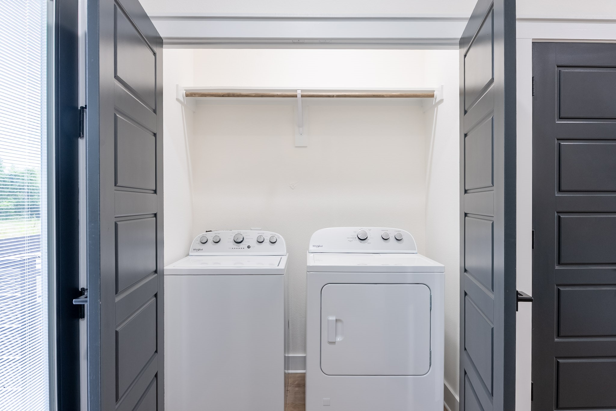 Convenient laundry area with modern washer and dryer, tucked behind elegant double doors for a sleek and functional space.