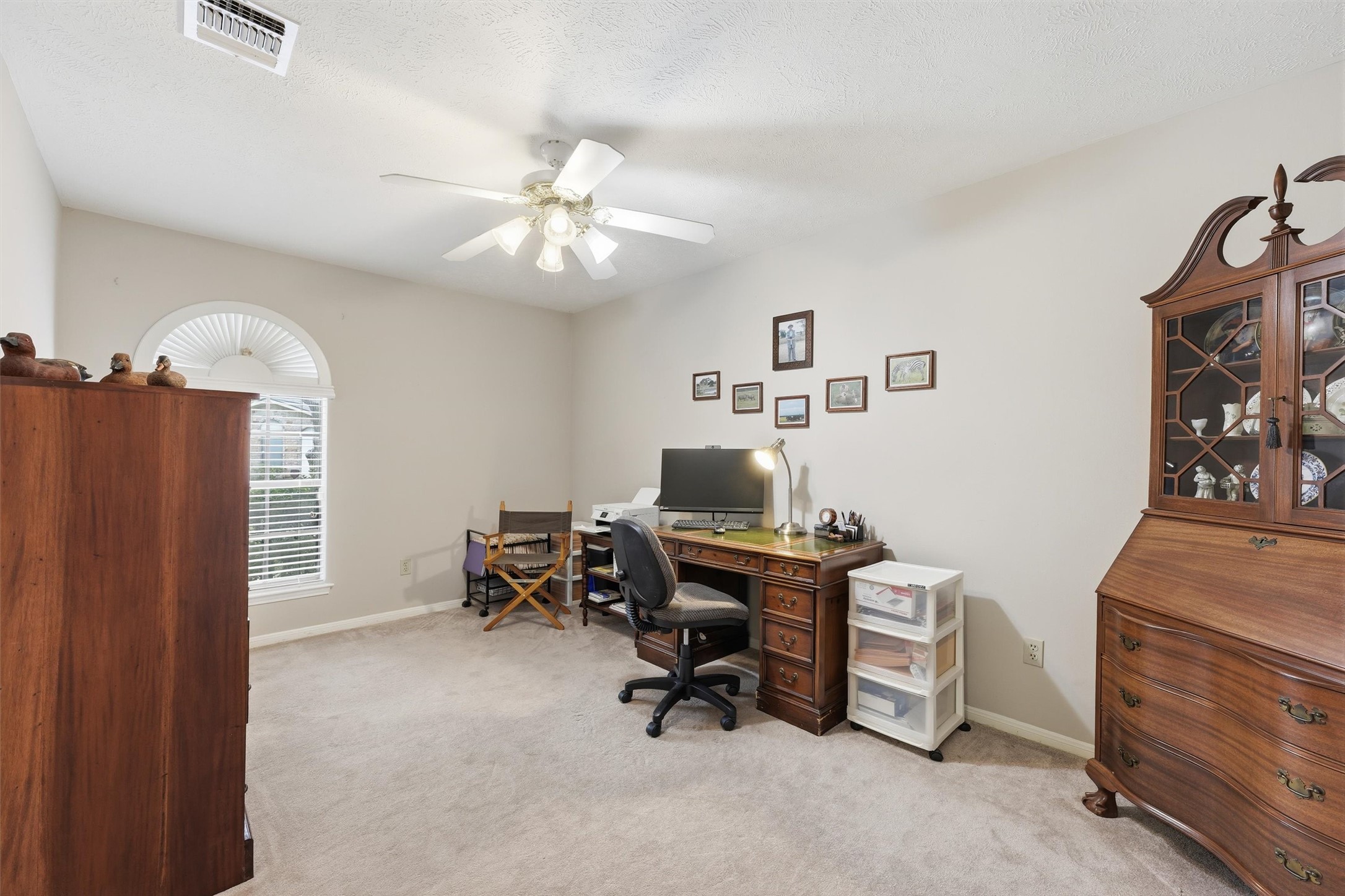 The split floor plan offers two flexible secondary bedrooms at the front of the home.  This one is currently used as an office space & features a ceiling fan & walk-in closet with shelving.