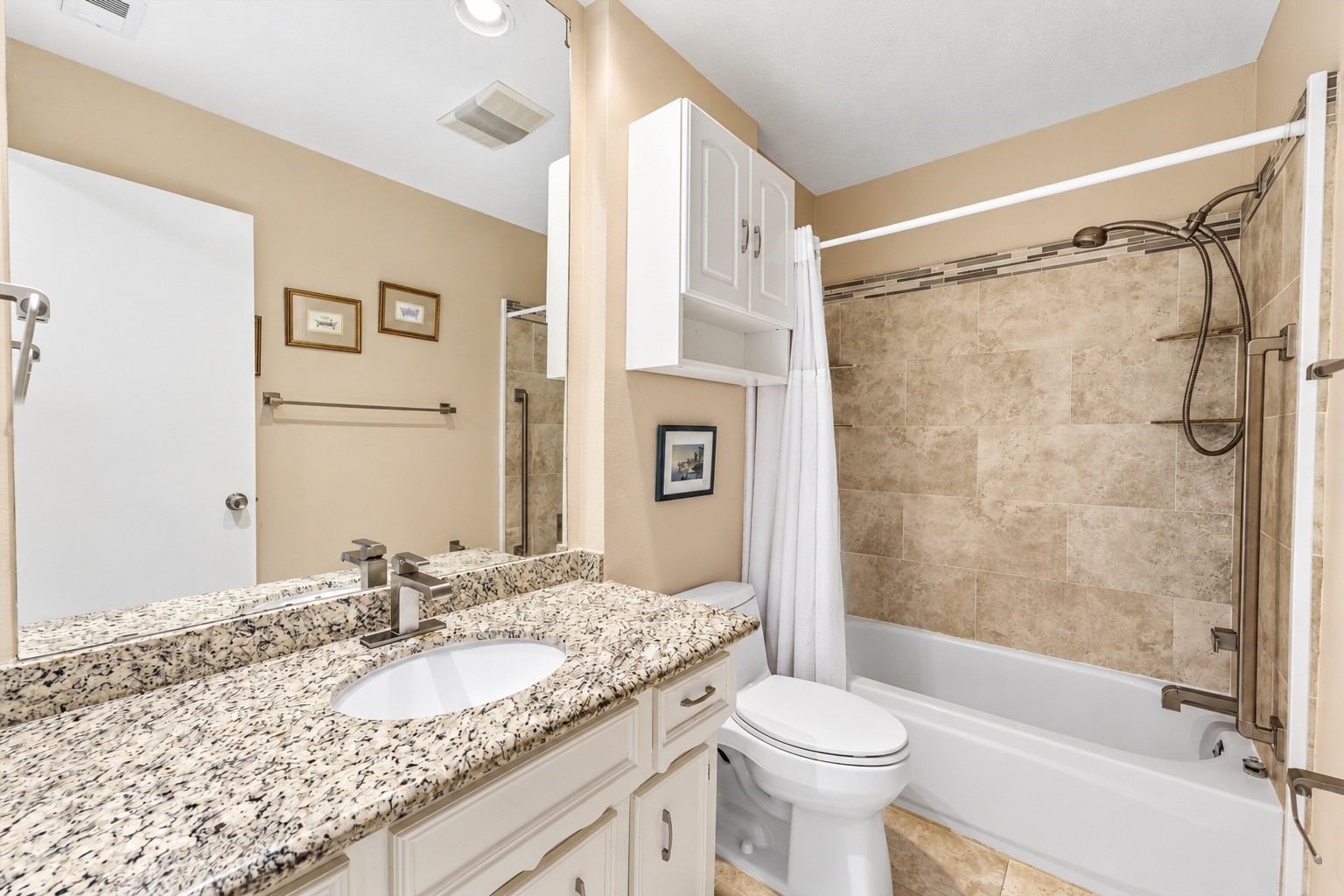 Secondary hall bath has been updated with granite counter, undermount sink, upgraded fixtures, tile flooring & tile bathtub surround.