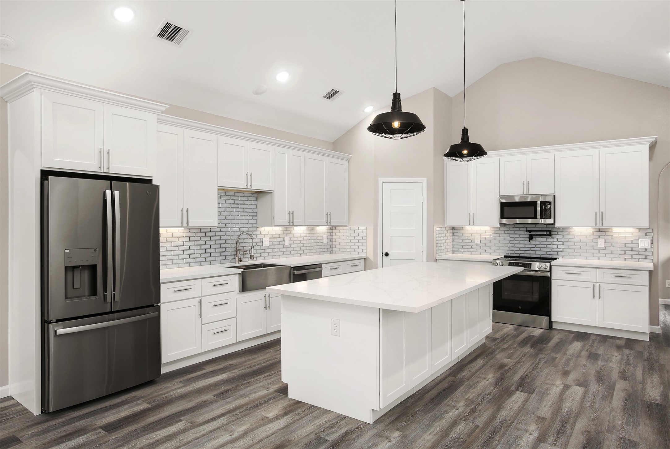 Beautiful kitchen with quartz countertops, glass tile backsplash, under cabinet lighting, stainless steel appliances, and oversized 9x5 island Beautiful kitchen with quartz countertops, glass tile backsplash, under cabinet lighting, stainless steel appliances, and oversized 9x5 island