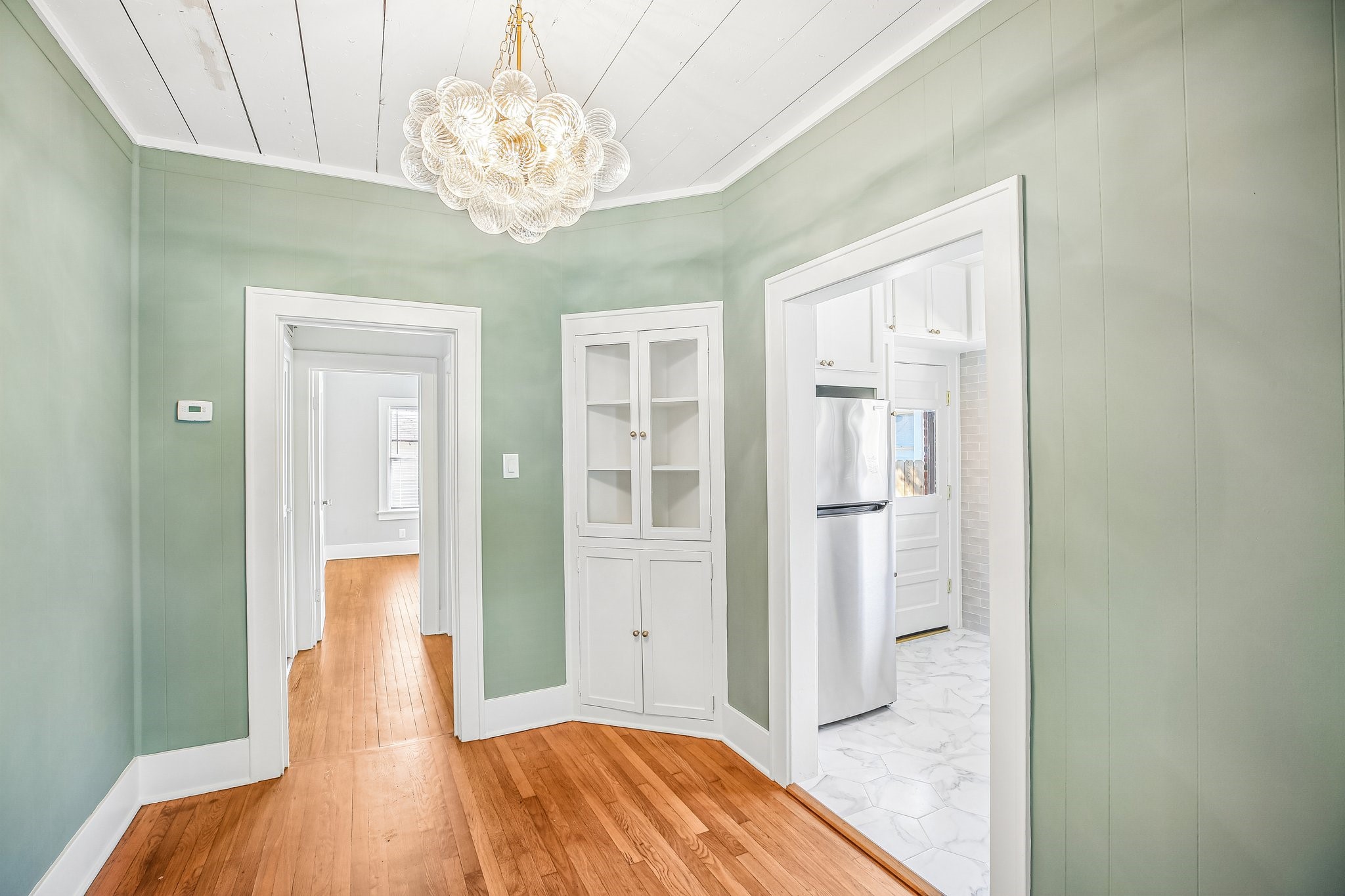 The dining room is darling with it's original corner hutch, shiplap ceilings and whimsical chandelier.