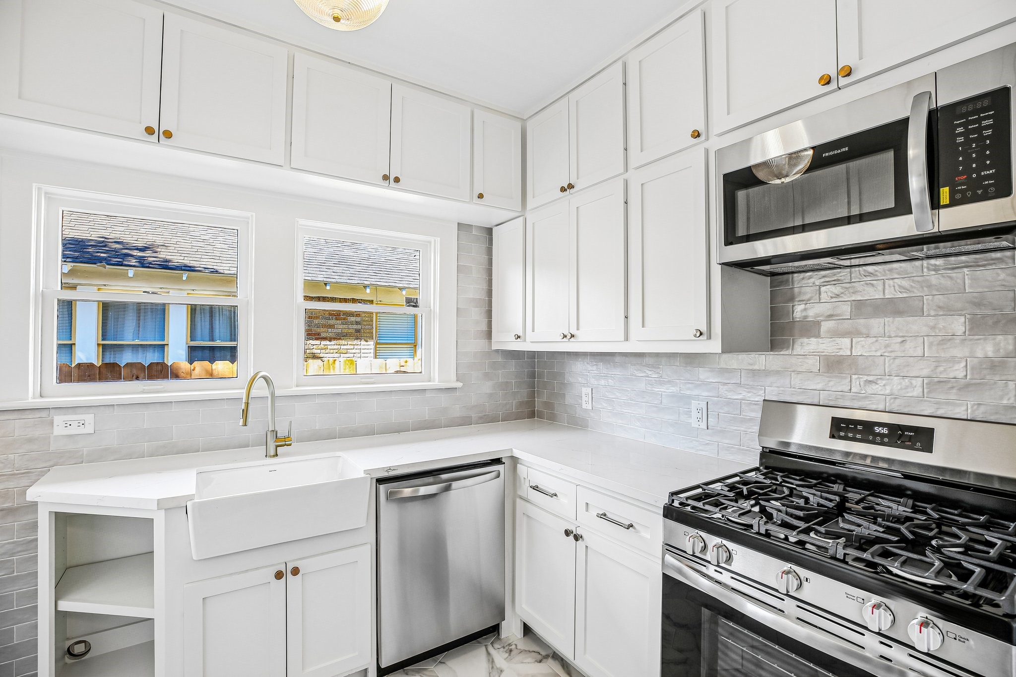 The kitchen is all-Heights with marble flooring and an updated version of the classic subway. Cabinets, also all-new, are crafted on site and done in the traditional "old Heights" Shaker style. The sink is farmhouse style. There is a door to the backyard to the left of the angled cabinet straight ahead (not pictured).