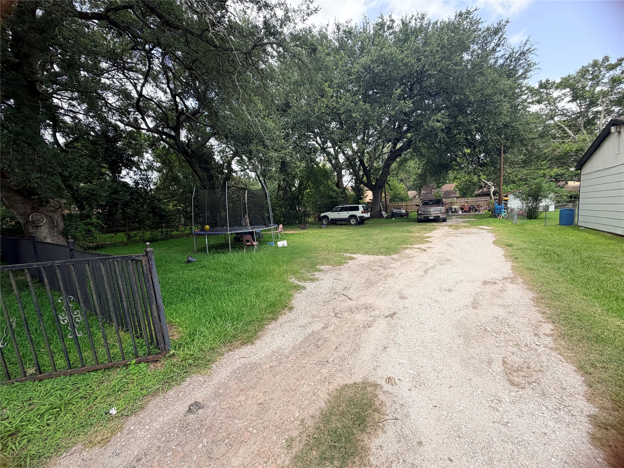 The existing driveway provides convenient access to the property, with mature trees adding character and natural shade.