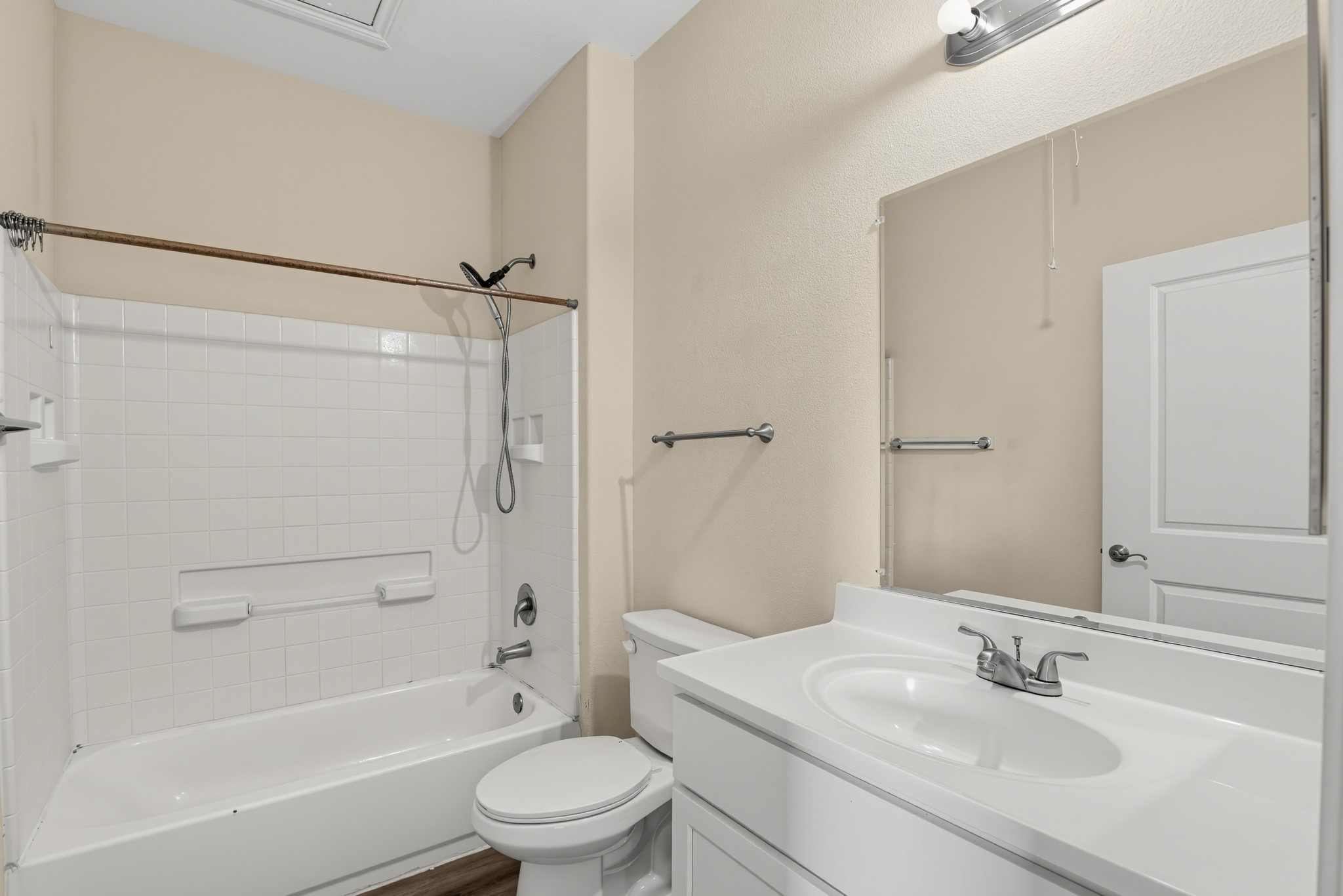 The bathroom features a cultured marble vanity, an elongated commode, and a tile-enclosed tub and shower.
