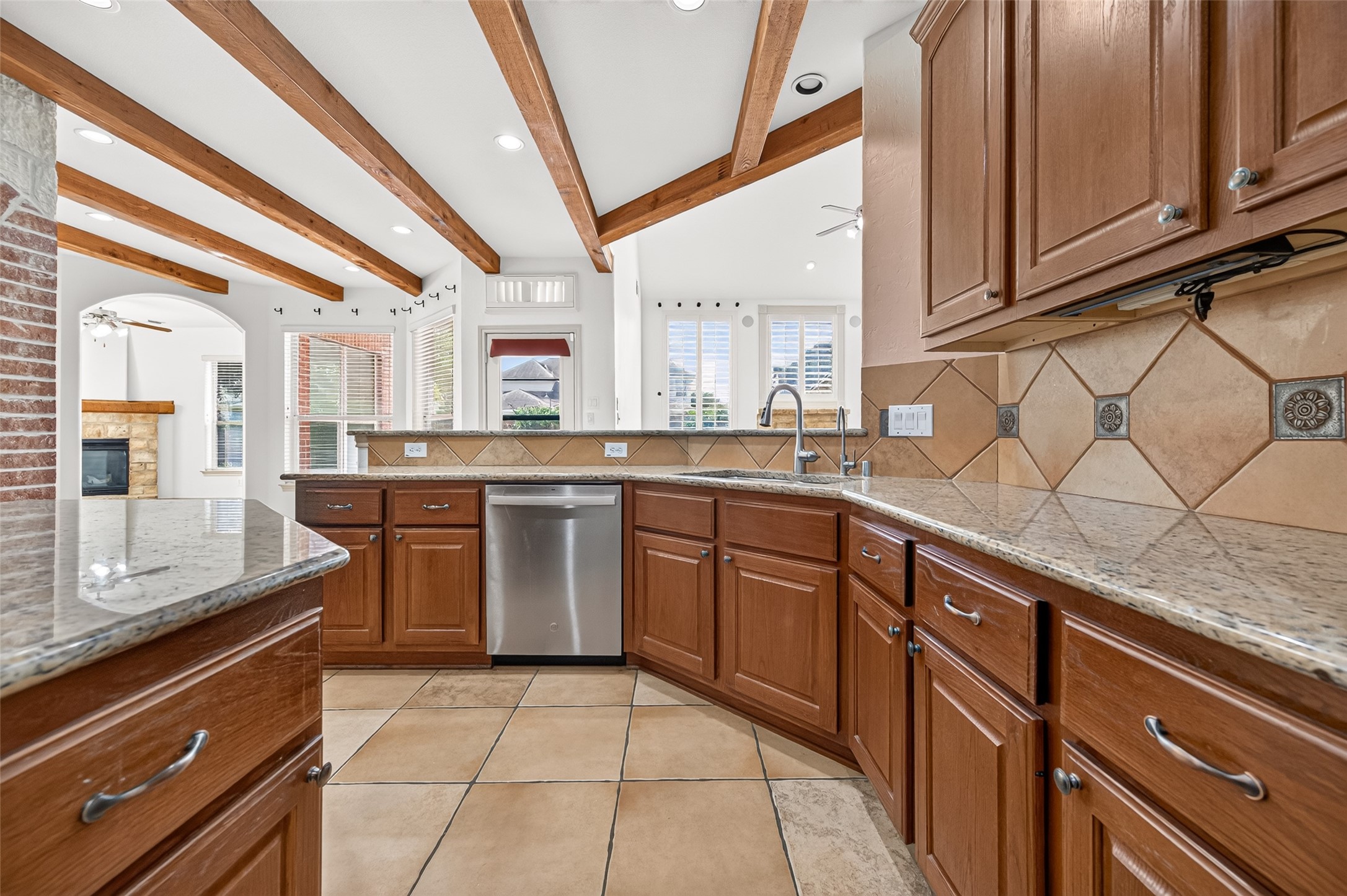 Spacious kitchen with elegant wooden cabinets, granite countertops, and stainless steel appliances, accented by exposed beams and natural light from large windows. Spacious kitchen with elegant wooden cabinets, granite countertops, and stainless steel appliances, accented by exposed beams and natural light from large windows.