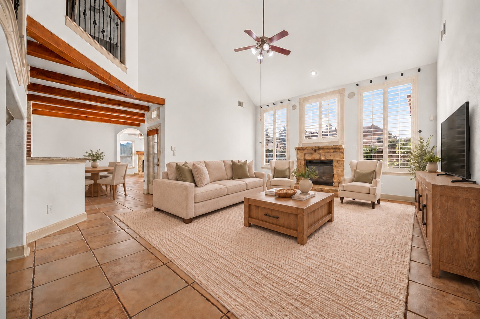 Spacious living room with high ceilings, a cozy stone fireplace, and abundant natural light from large windows, seamlessly connected to the kitchen and breakfast room. Spacious living room with high ceilings, a cozy stone fireplace, and abundant natural light from large windows, seamlessly connected to the kitchen and breakfast room.