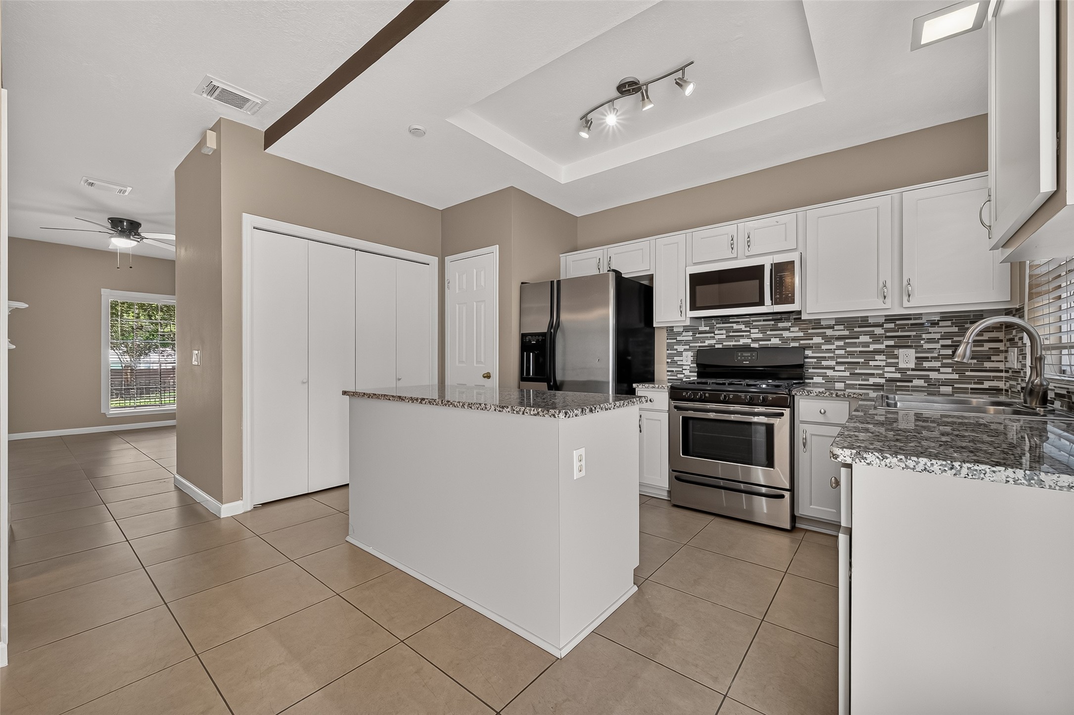 Updated kitchen featuring granite countertops, white cabinetry, stainless-steel appliances, decorative tile backsplash, and generous counter space. Updated kitchen featuring granite countertops, white cabinetry, stainless-steel appliances, decorative tile backsplash, and generous counter space.