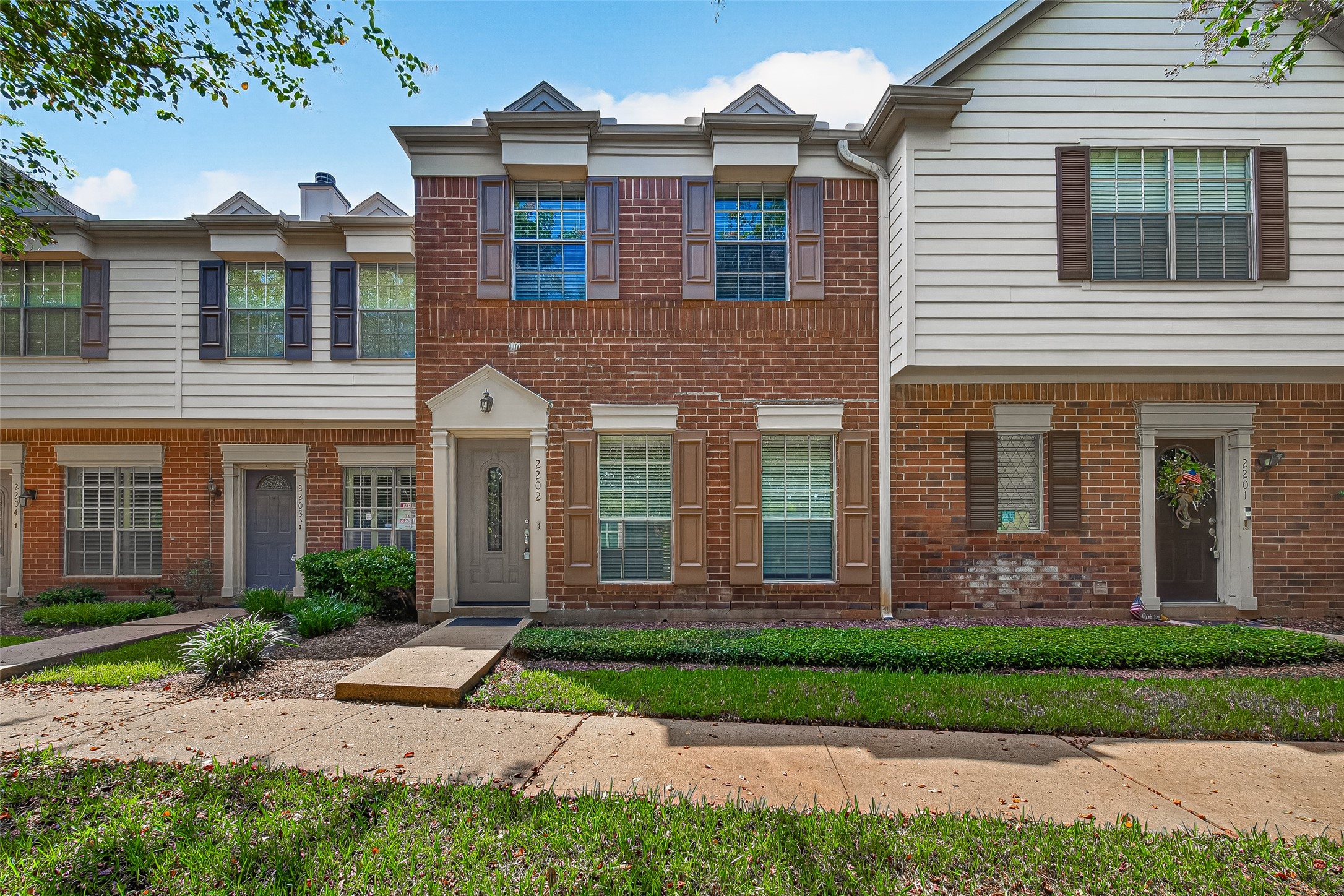 Attractive two-story townhouse with classic brick exterior, mature landscaping, and a welcoming front entry. Attractive two-story townhouse with classic brick exterior, mature landscaping, and a welcoming front entry.