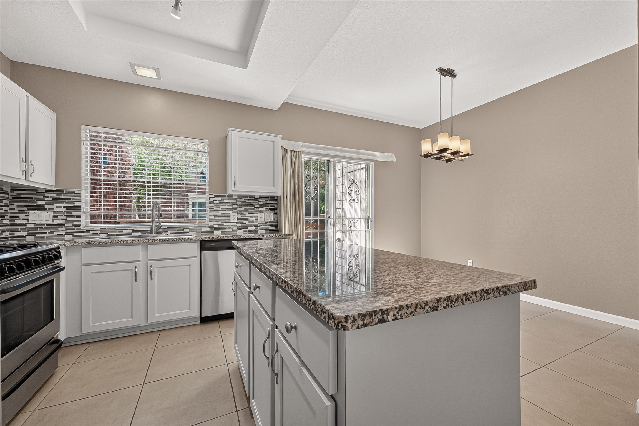 Well-appointed kitchen showcasing granite countertops, stainless-steel appliances, decorative backsplash, abundant cabinetry, and convenient island workspace.
