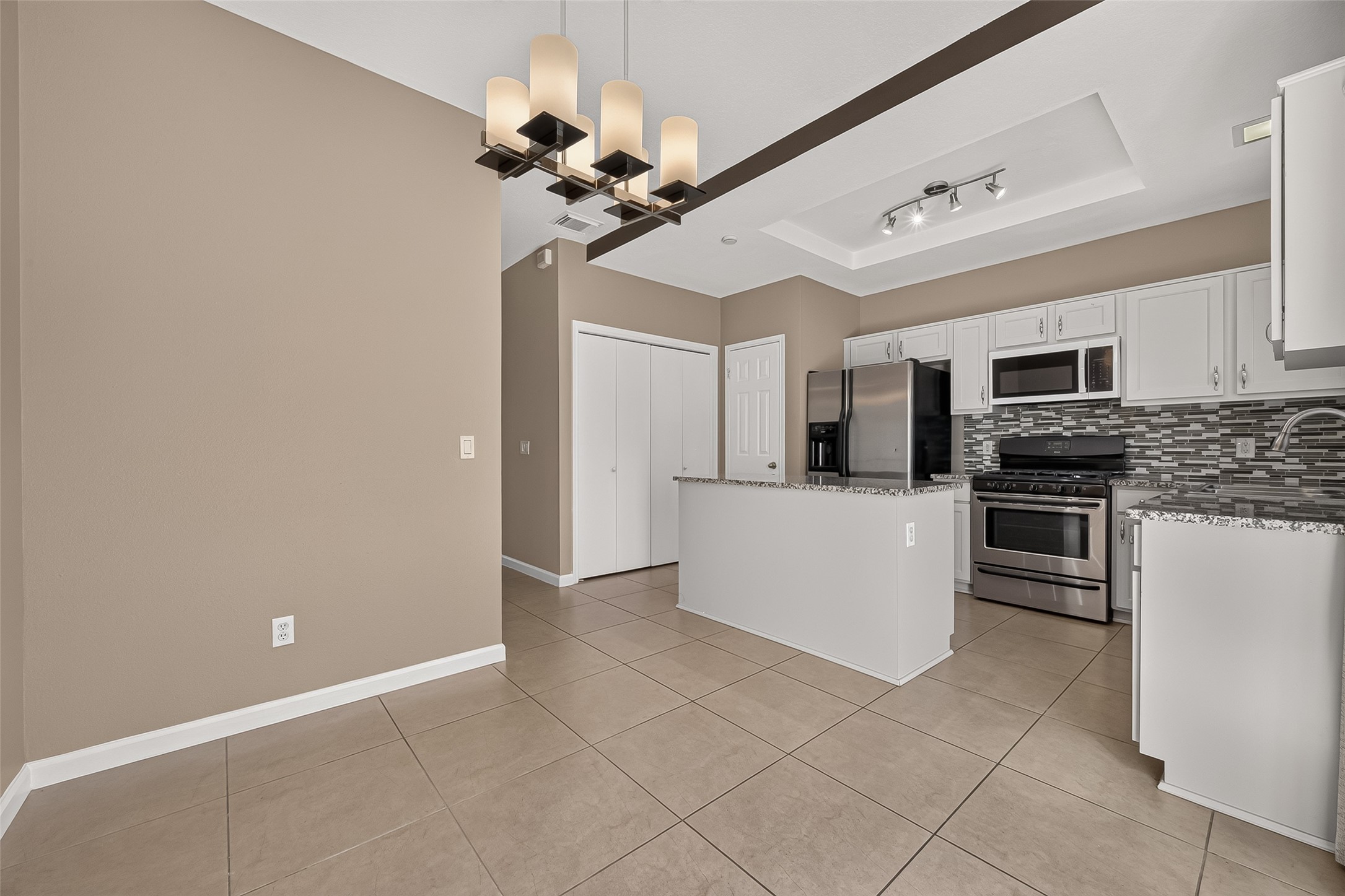 Spacious kitchen and dining combination offering granite countertops, stainless-steel appliances, decorative backsplash, abundant cabinetry, and an open layout ideal for everyday living.