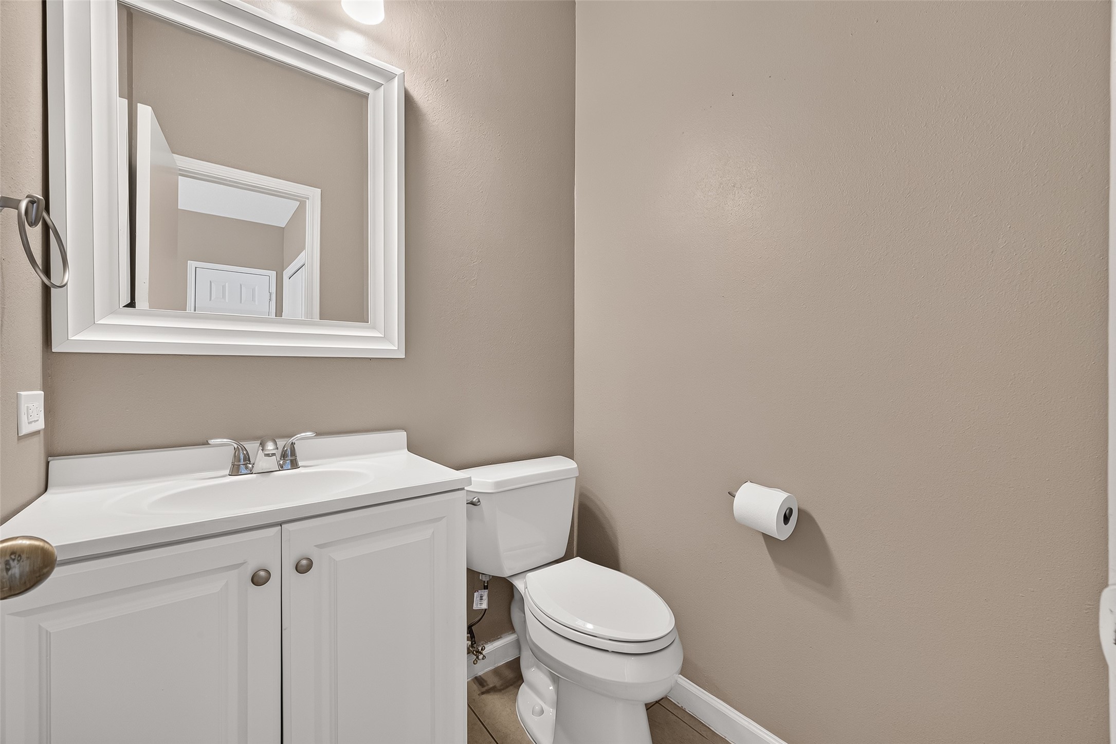 Convenient half bath featuring a bright vanity, framed mirror, neutral finishes, and easy access for guests.
