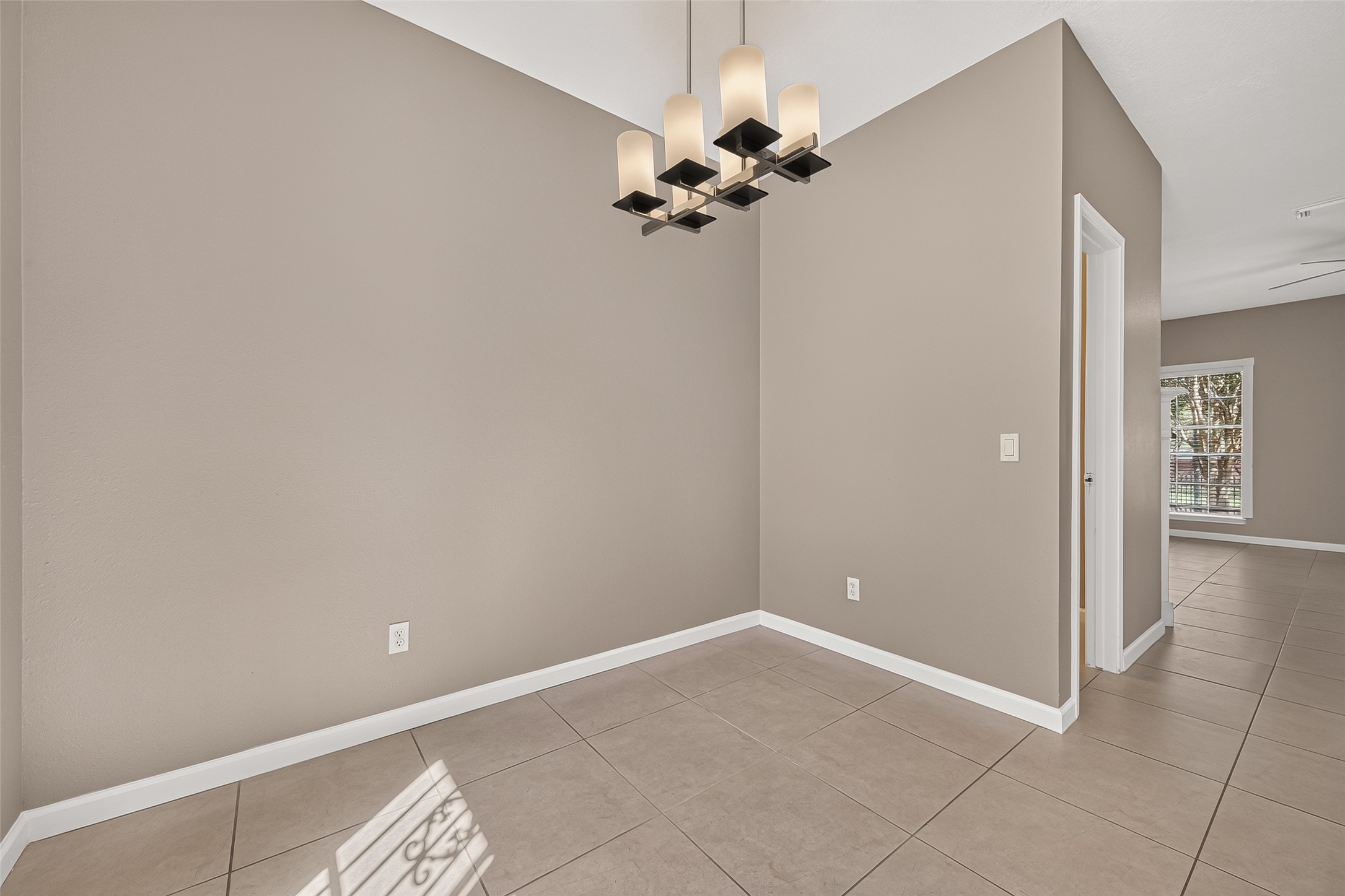 Dedicated dining area with tile flooring, neutral finishes, contemporary chandelier, and convenient access to the kitchen and living areas.