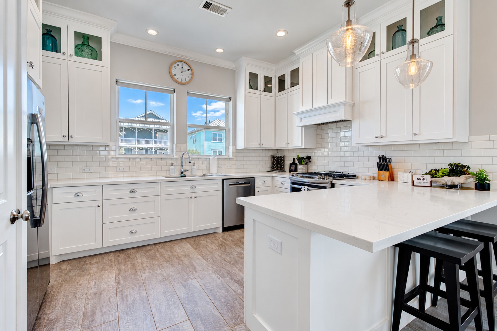 The kitchen with shaker cabinets, quartz countertops, classic subway tile backsplash, and breakfast bar with pendant lighting.