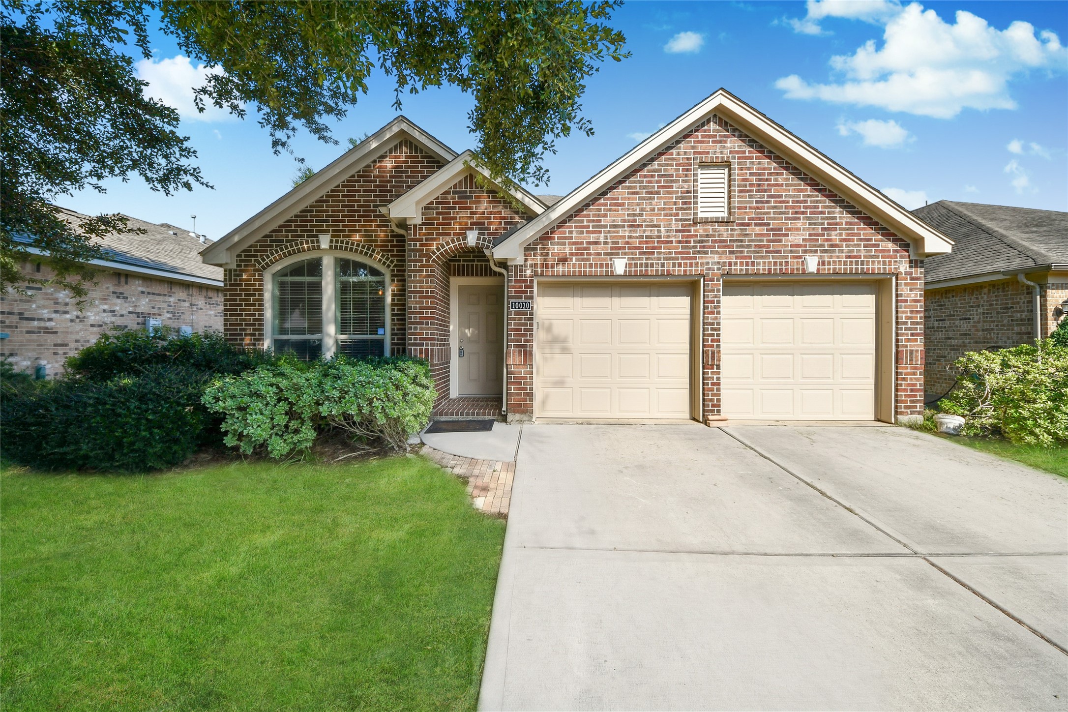 Charming brick home with a welcoming facade, featuring a neatly manicured lawn and a spacious two-car garage.