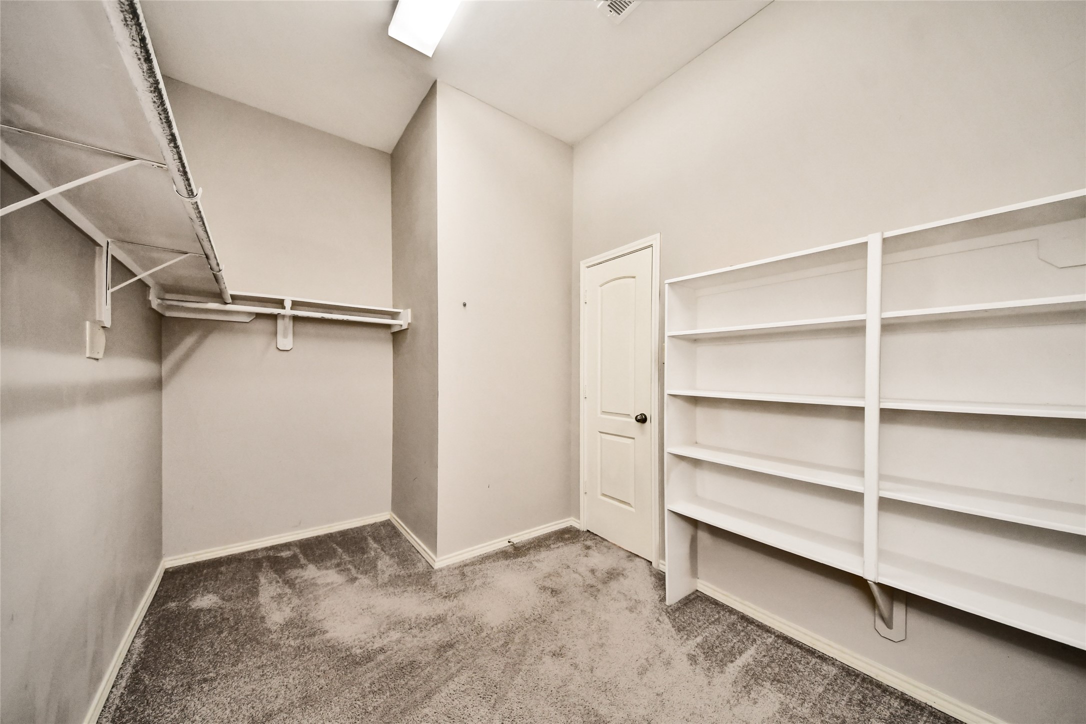 Spacious walk-in closet featuring ample shelving and hanging space, perfect for organized storage solutions.