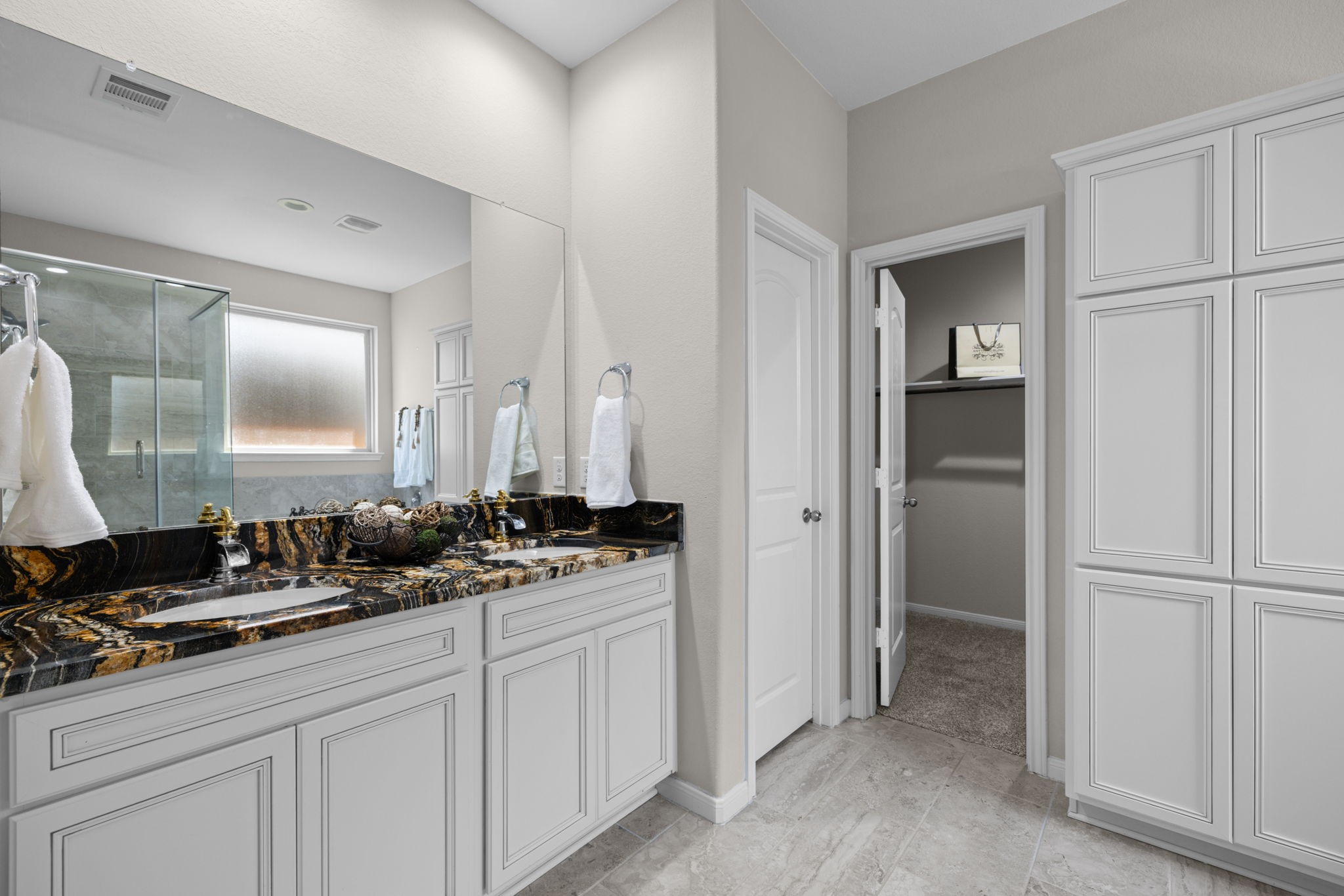 The ensuite bath has high vanity with double sinks. The tile floors are a pretty neutral and the built ins make great extra storage