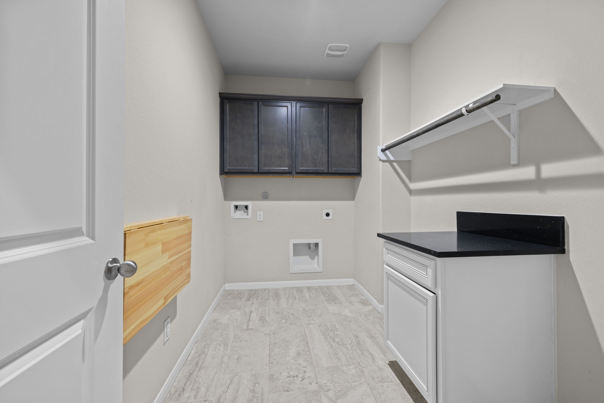 The laundry room is just next to the garage entry and drop zone. This is a large room with folding table and cabinets.