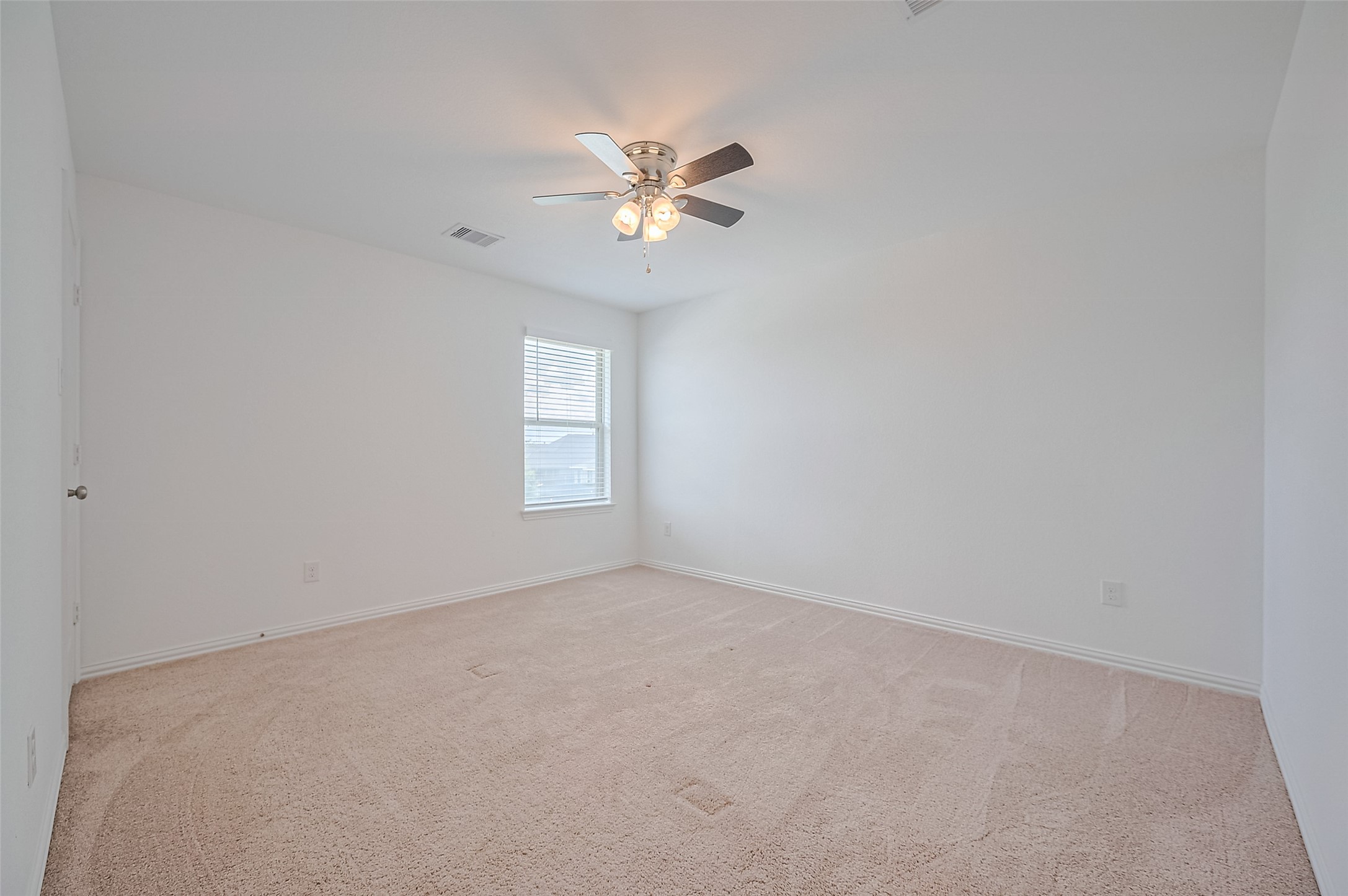 Spacious bedroom with plush carpet and abundant natural light.