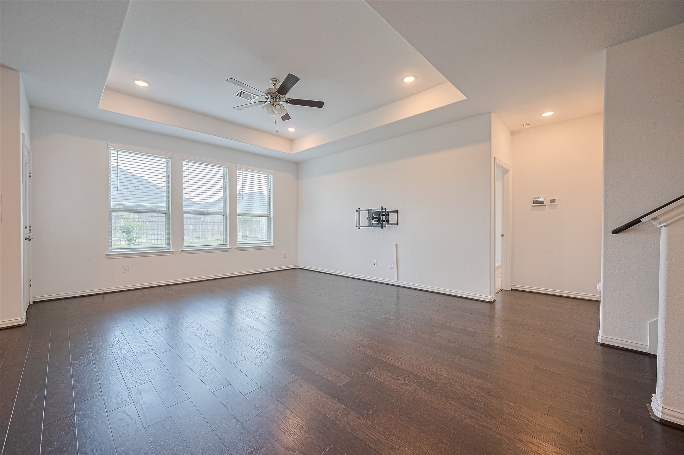 Spacious living room features large windows and a tray ceiling.