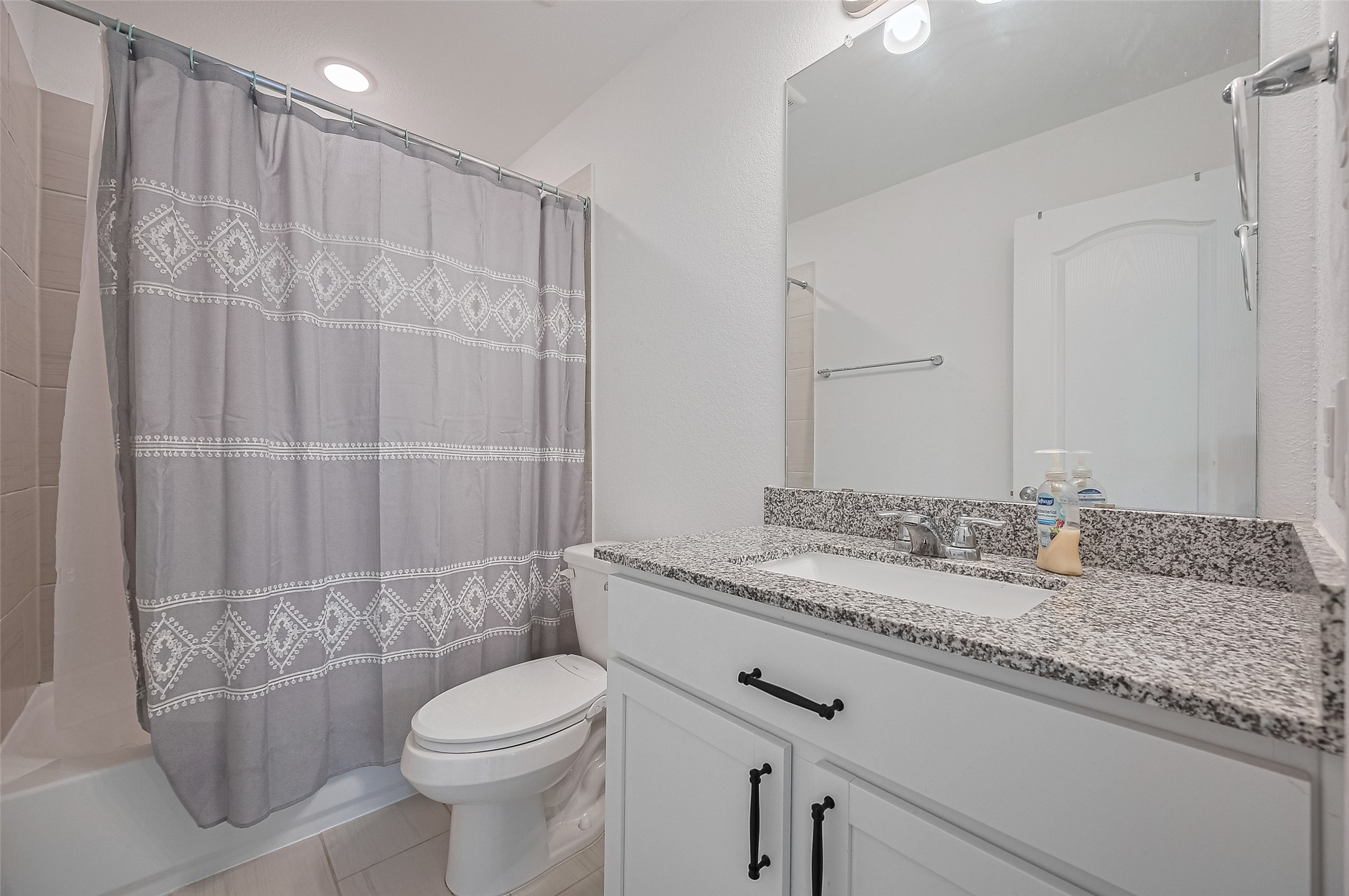 Bathroom features a granite countertop, undermount sink, and white cabinetry.