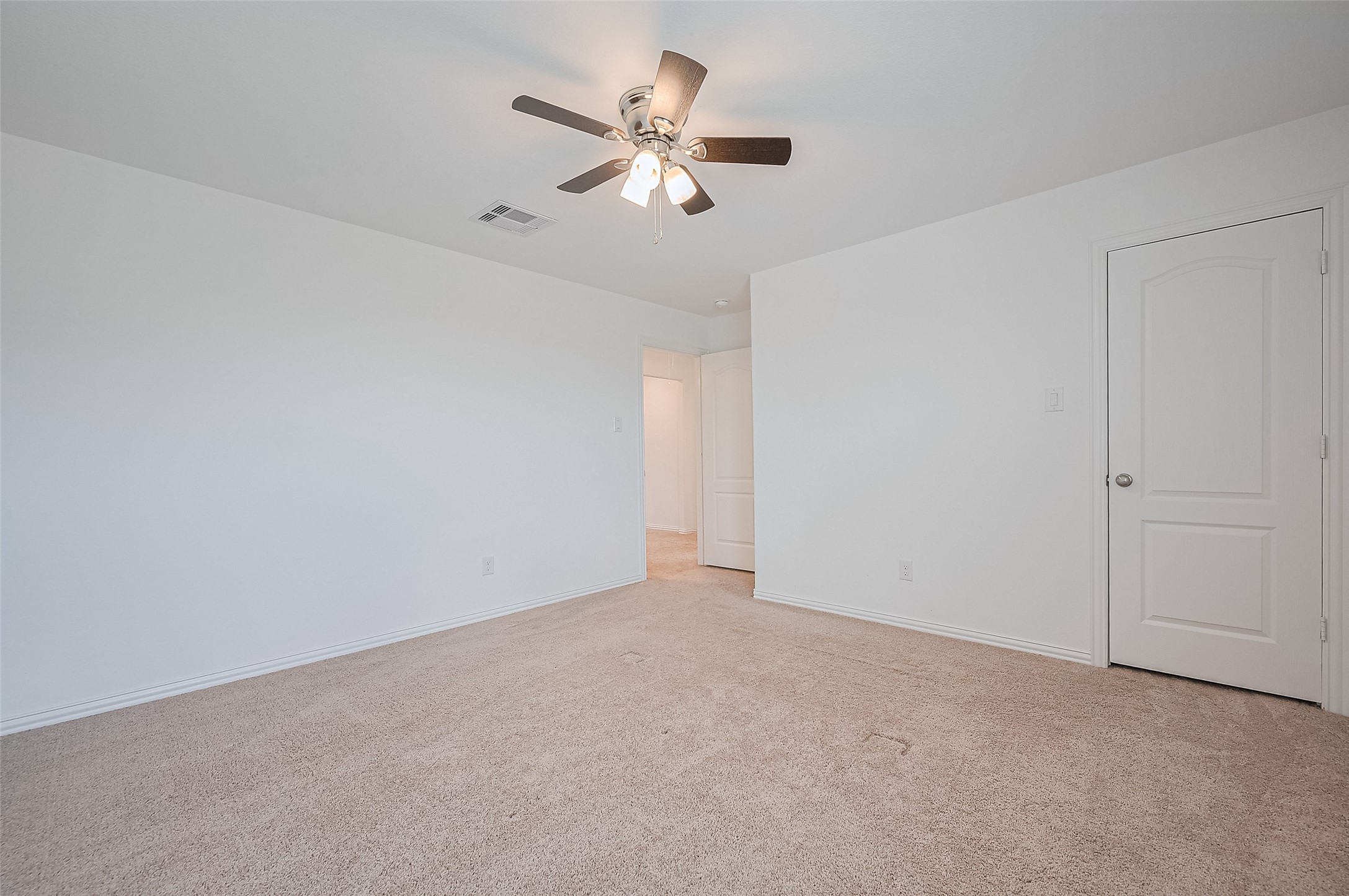 Spacious room with a simple closet door and an additional door leading to bathroom.
