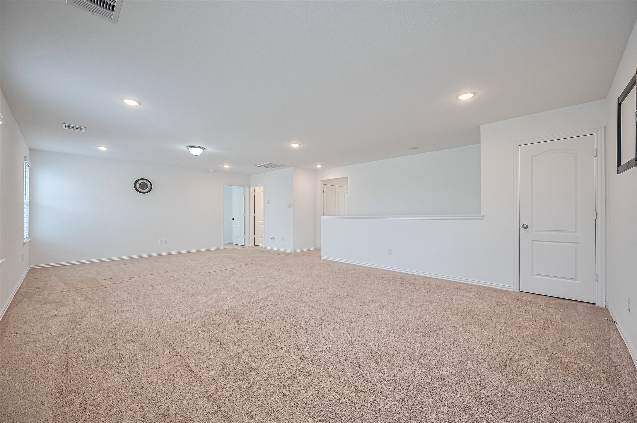 Spacious room features recessed lighting, and ample natural light from windows.