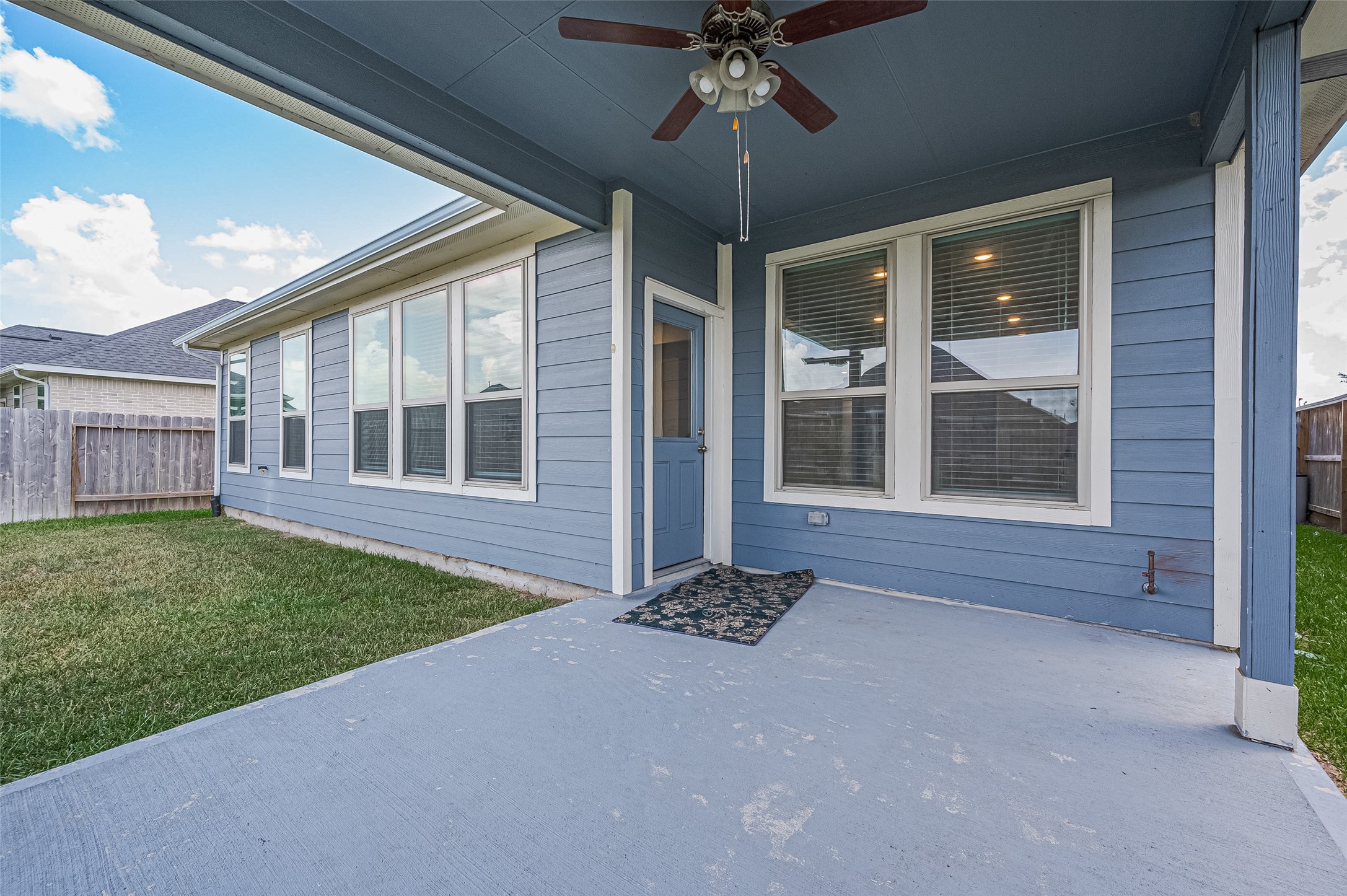 Cozy covered patio with a concrete flooring and adjacent grassy yard area.