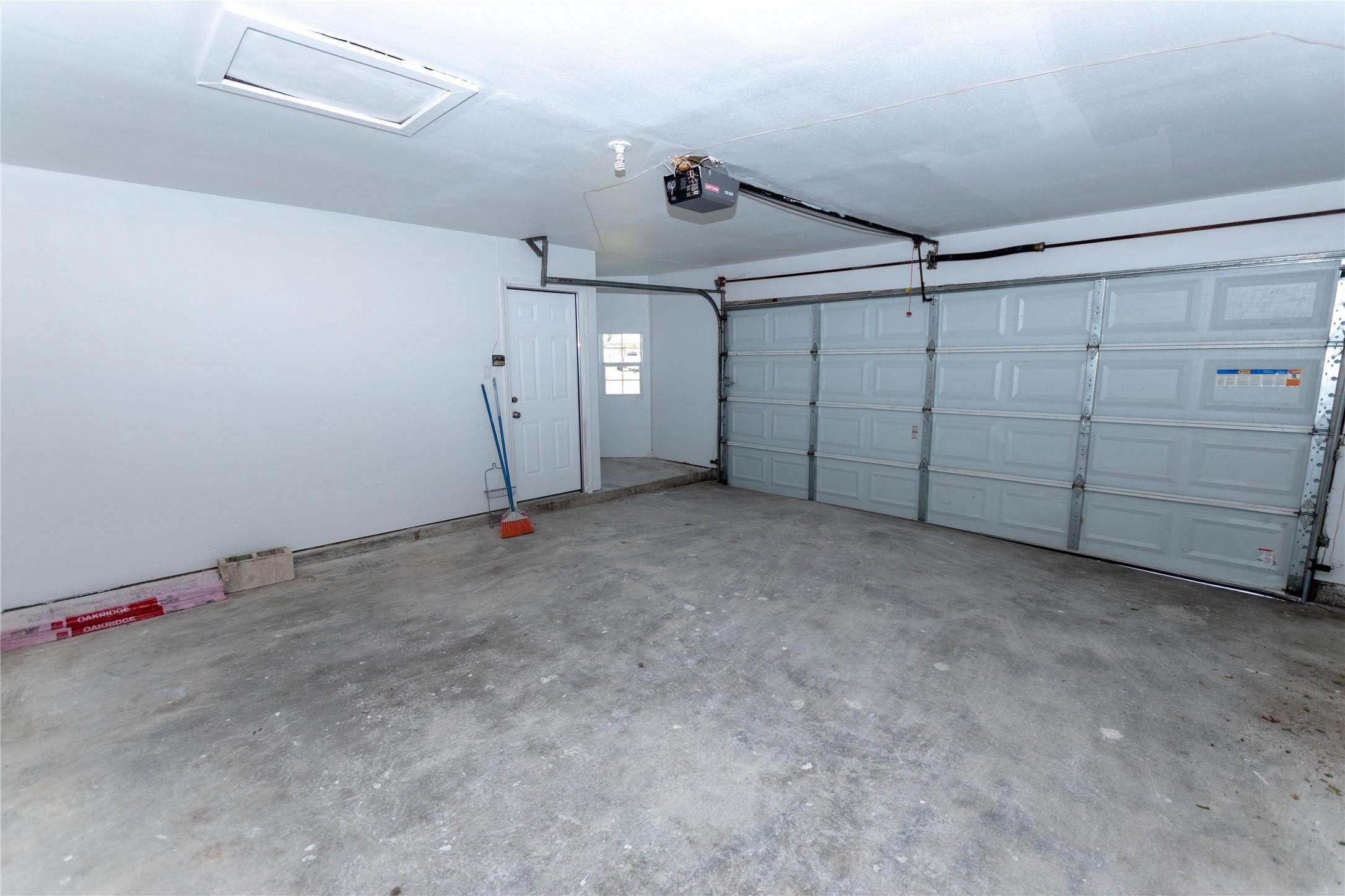 Spacious two-car garage with plenty of storage potential, featuring a clean concrete floor and easy access through a side door and automatic garage door.
