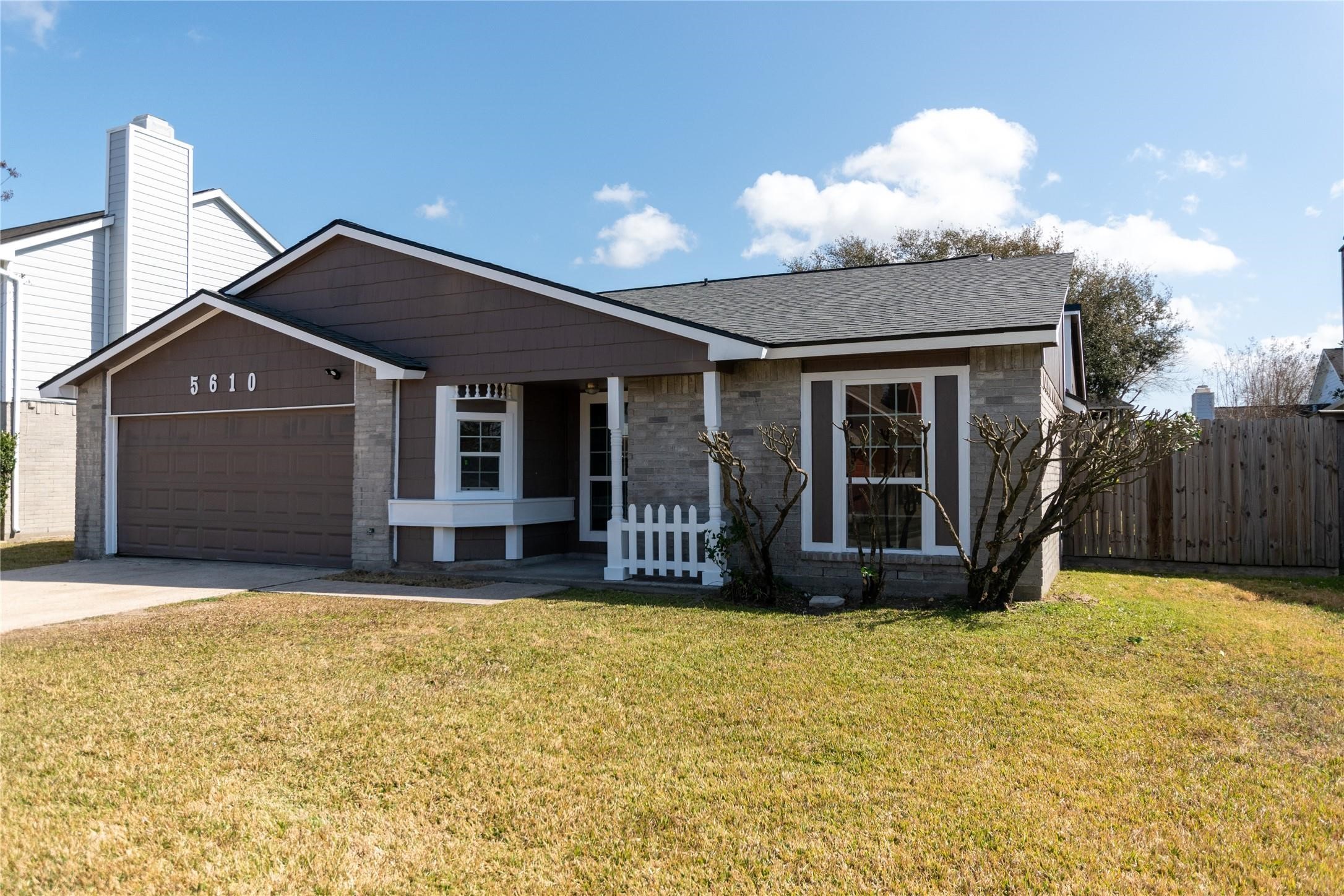 Charming single-story home with a welcoming front porch, attached garage, and neatly landscaped yard, offering great curb appeal.