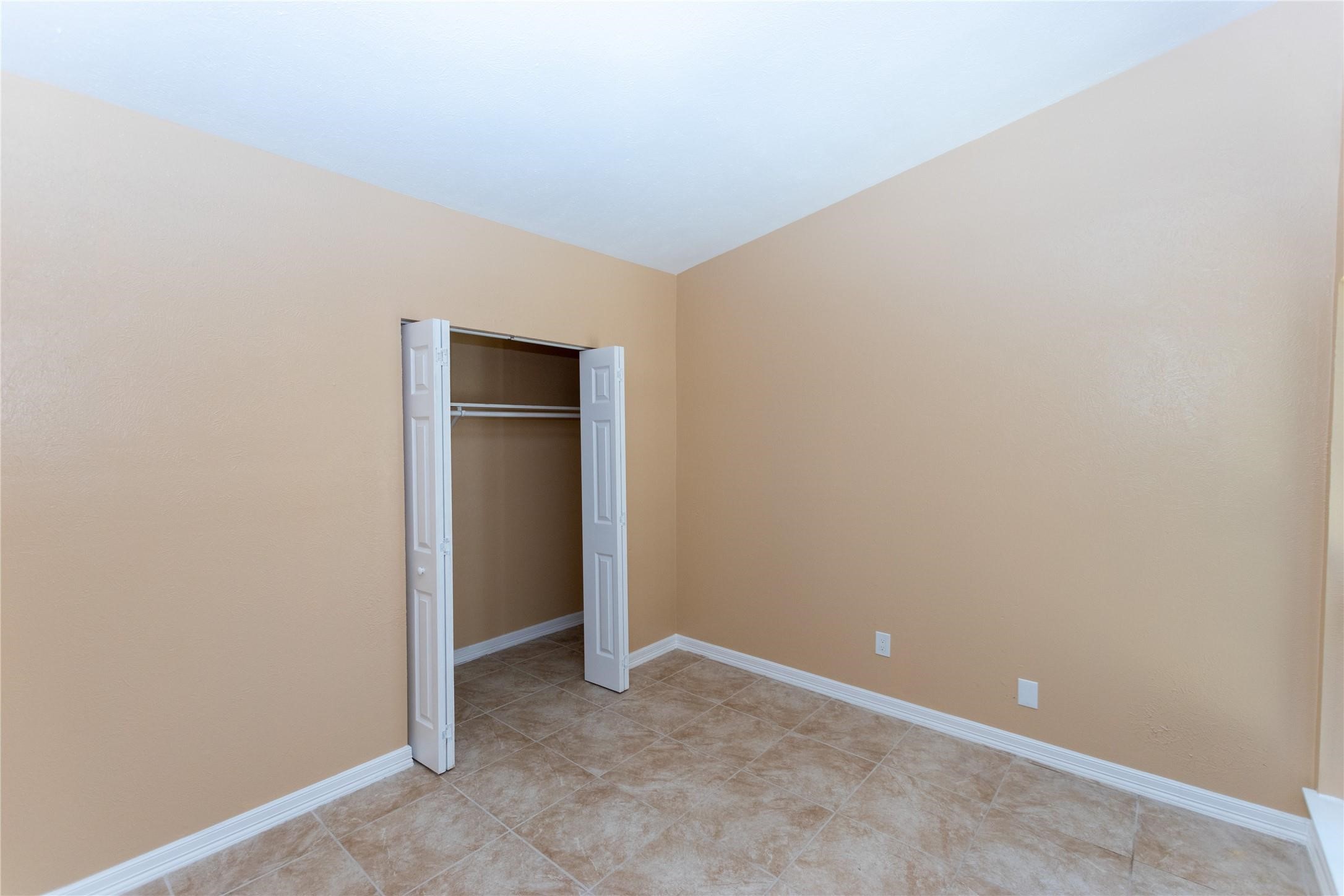 Cozy room with soft beige walls, tiled flooring, and a convenient closet with white folding doors.