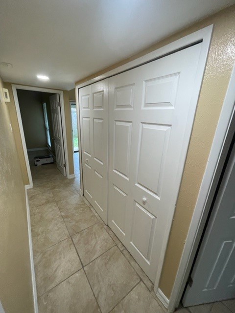Bright hallway with tiled flooring and ample closet space, leading to a cozy room with natural light.
