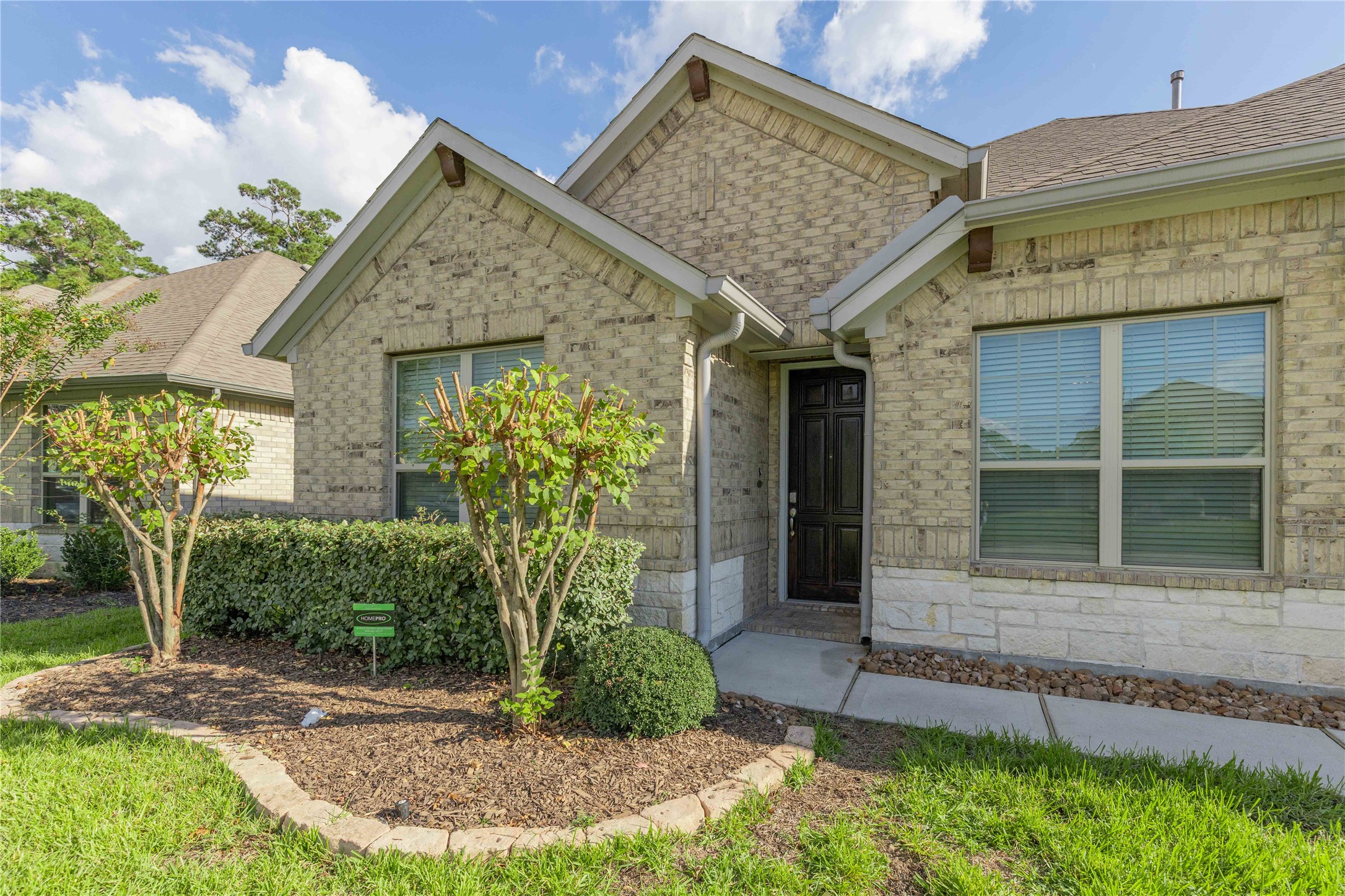 Charming brick home with a welcoming entryway, manicured landscaping, and large windows for natural light.