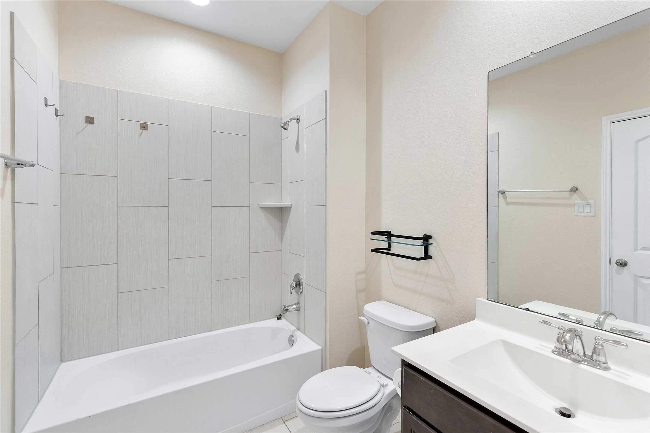 Sleek and modern, the secondary bathroom features elegant tile work, a spacious tub-shower combo, and a contemporary vanity, offering both style and functionality.