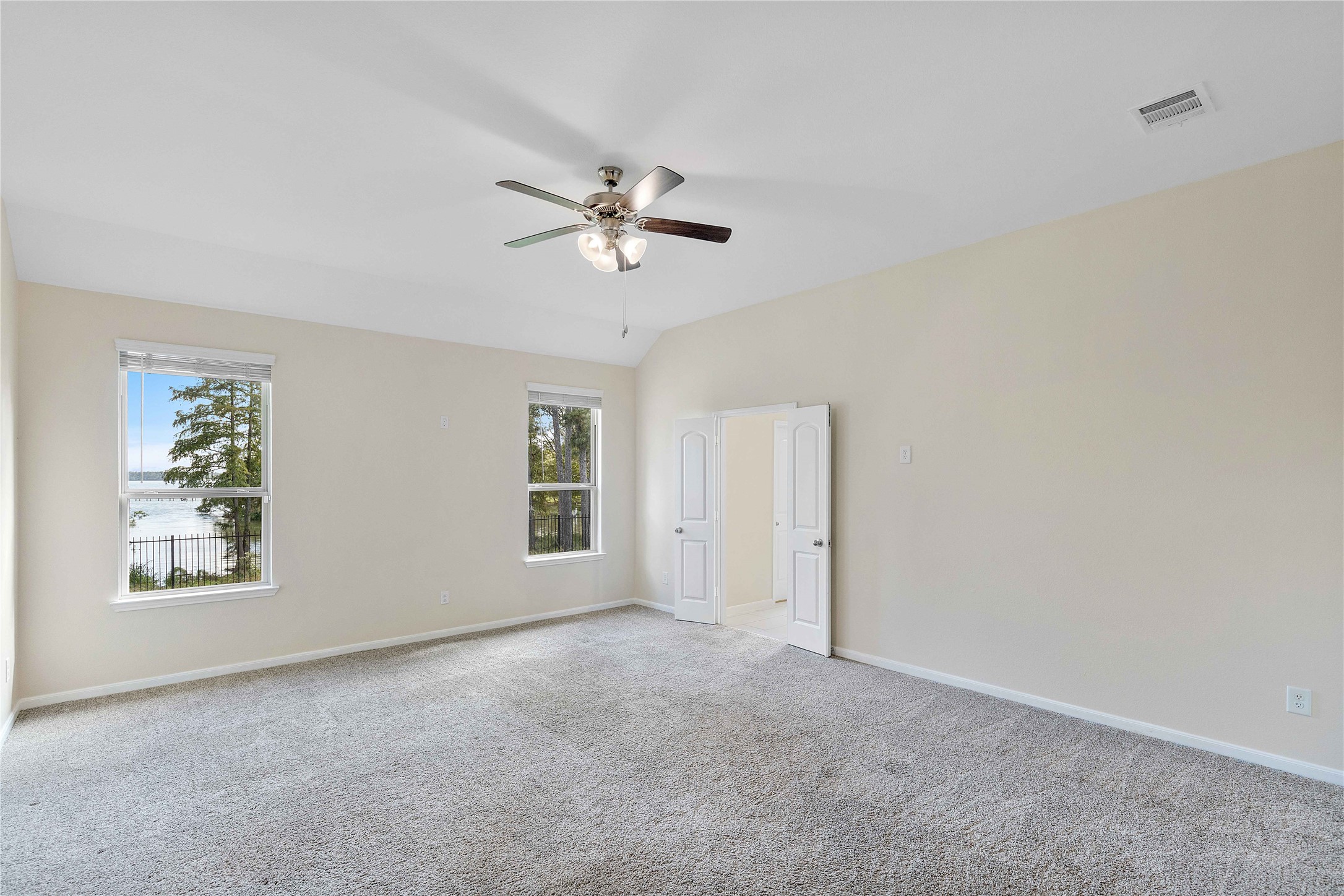Spacious Master bedroom with plush carpeting, featuring large windows that offer stunning waterfront views and abundant natural light.