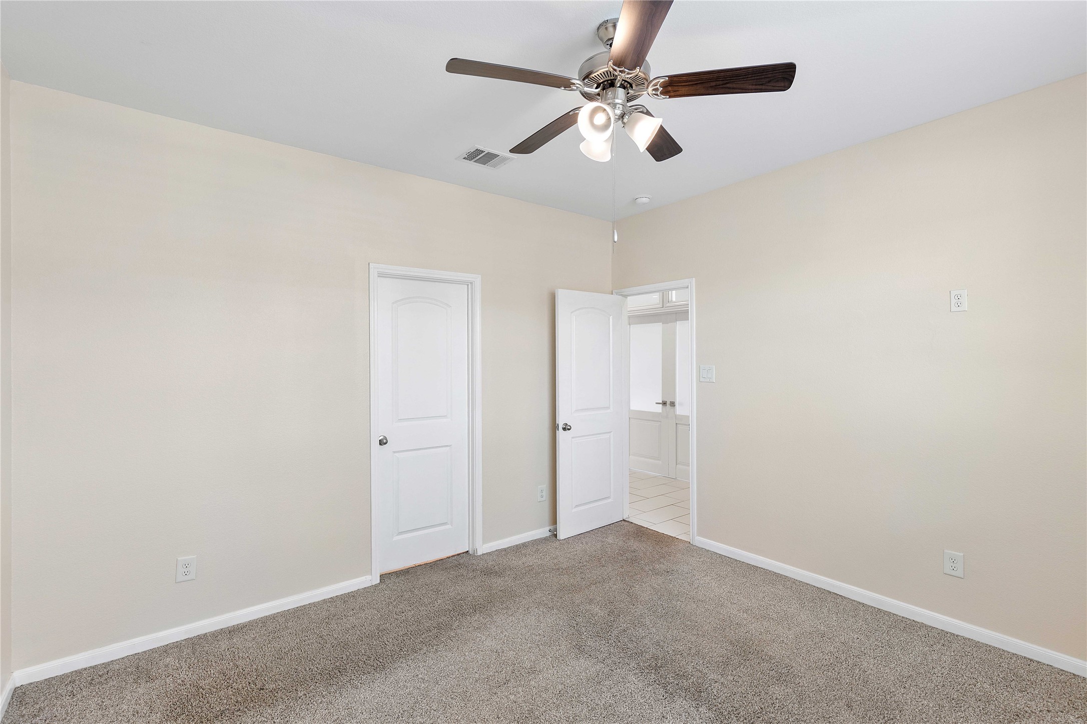 Charming bedroom with soft carpet, neutral walls, and a modern ceiling fan, offering a cozy and inviting atmosphere.