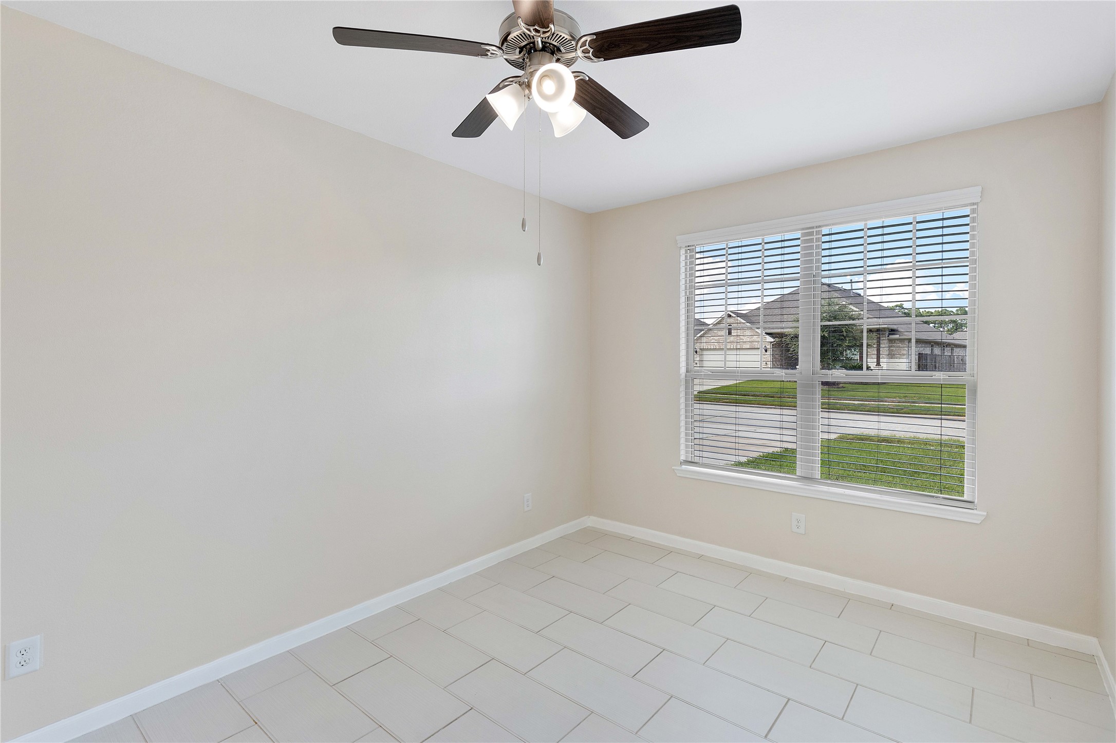 Bright room featuring large windows, neutral walls, and a ceiling fan, perfect for an office or guest bedroom.