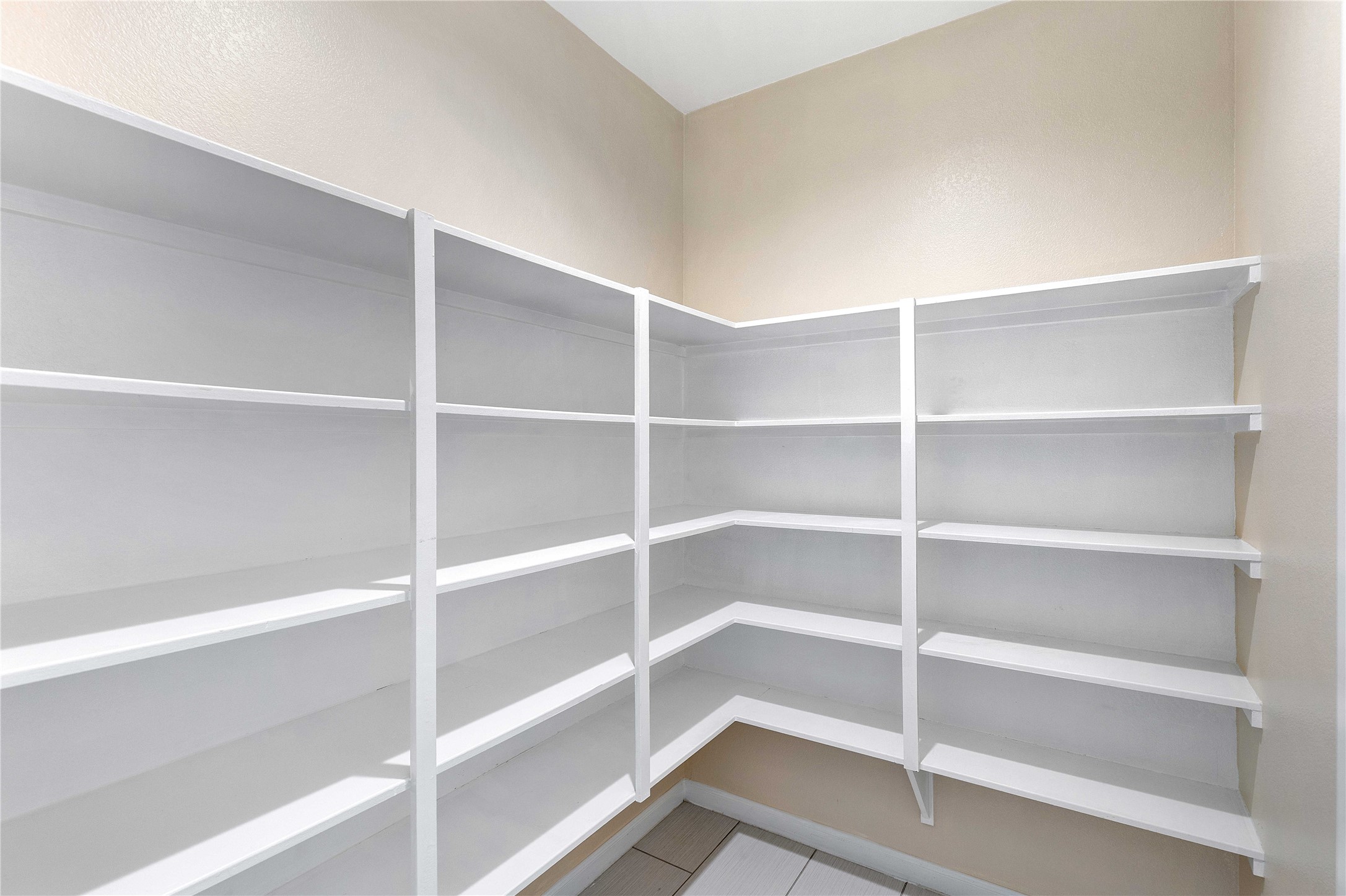 Spacious walk-in pantry with ample shelving for organized storage.