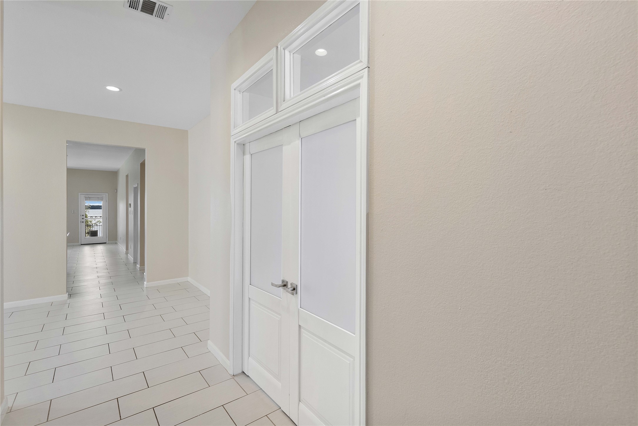 Bright and welcoming hallway with sleek tile flooring and elegant double doors, leading to Office/studio an inviting space filled with natural light.