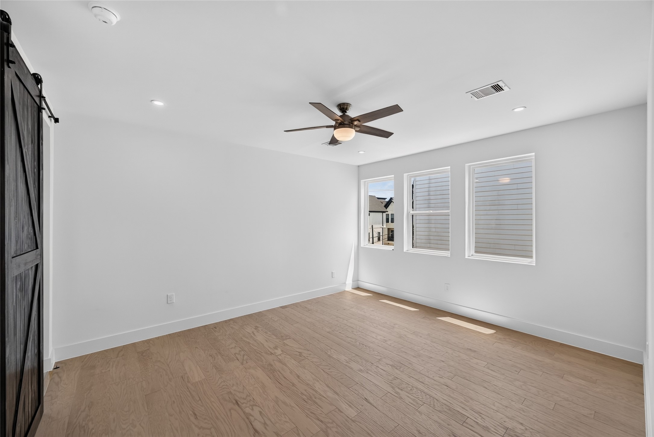 Primary bedroom with oversized windows and custom made barn door