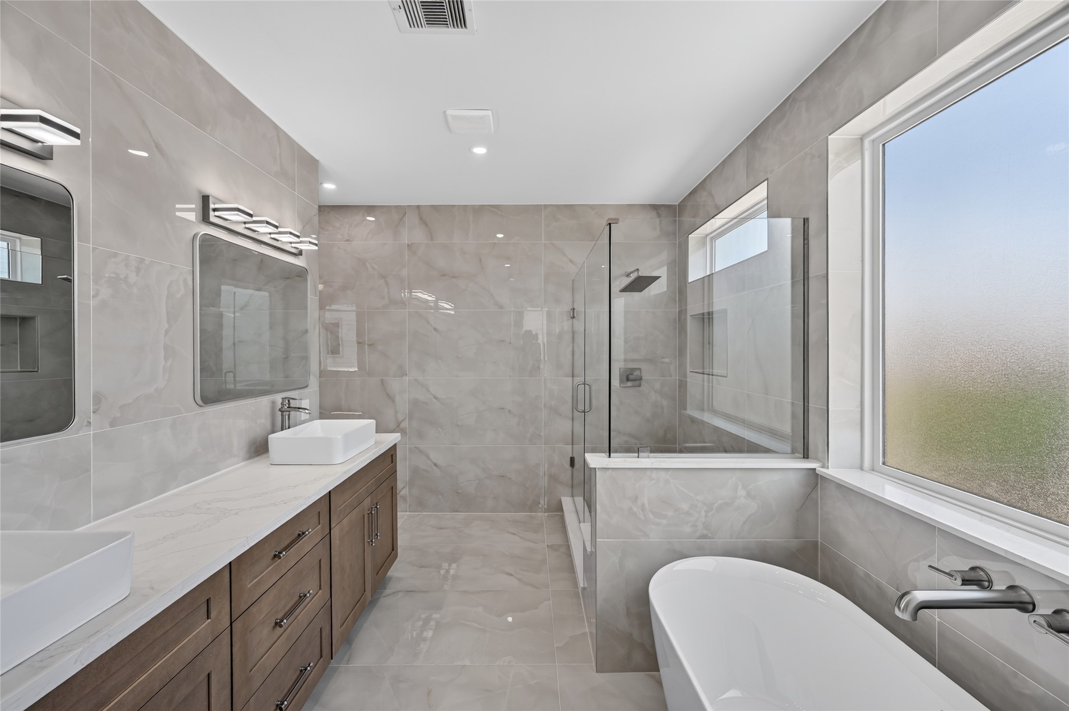 Primary Bathroom with creamy beige tile and custom cabinets with brush nickel hardware