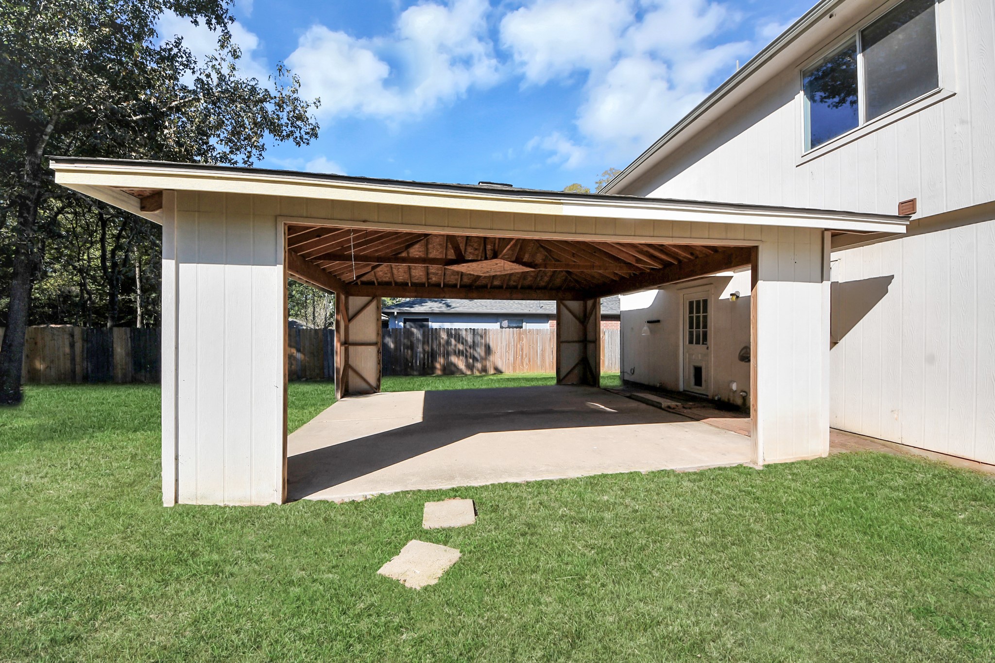 Covered patio attached to the home, nestled in a large yard, offering ample outdoor space.
