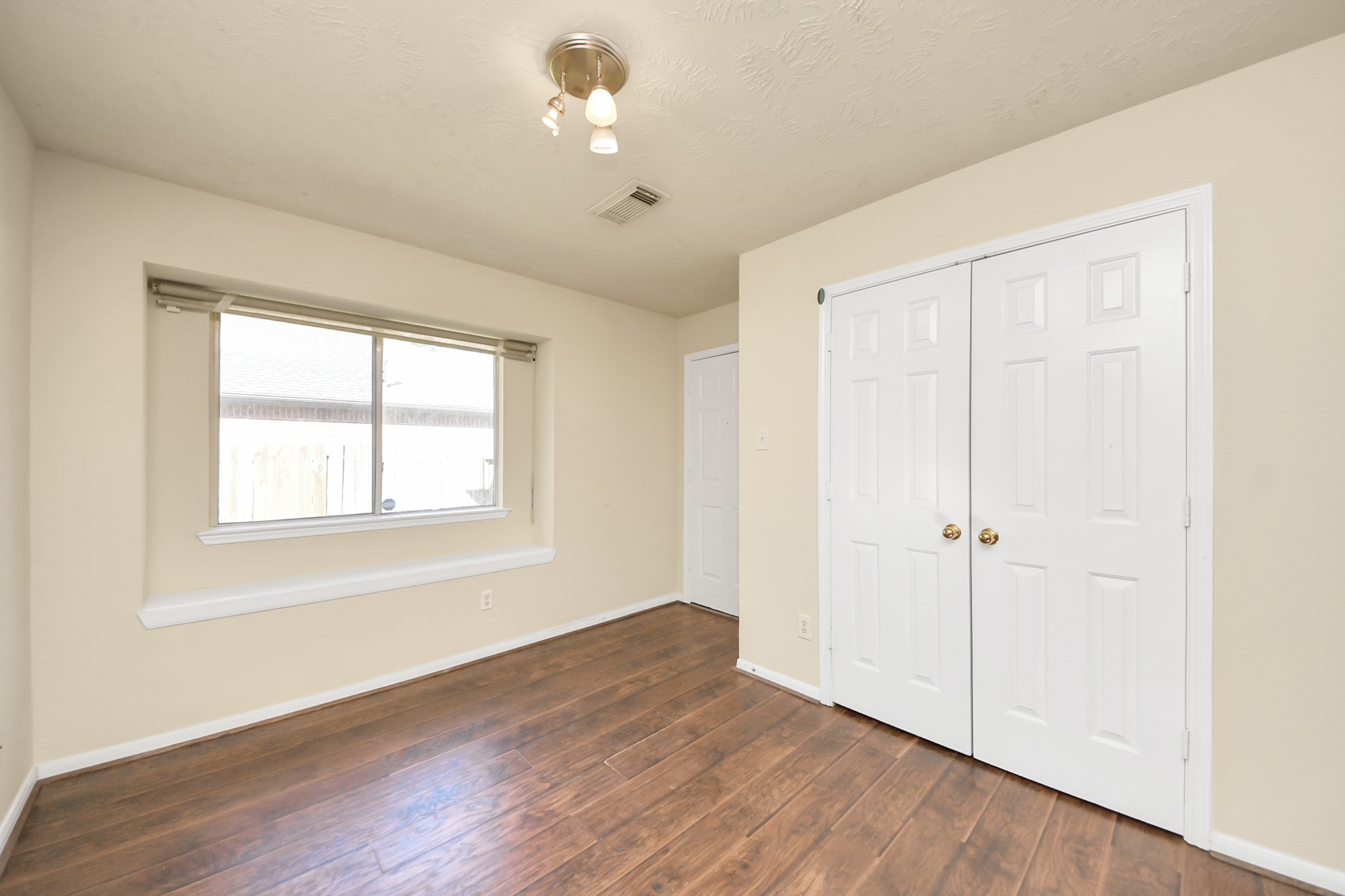 Bright breakfast room with hardwood floors, double pantry, and a large window offering natural light. Door leading to garage access.
