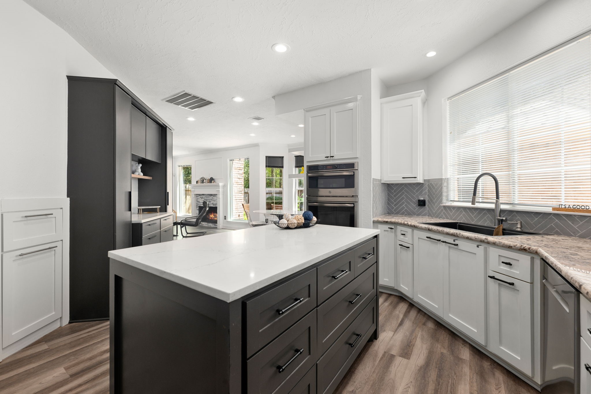 Modern kitchen featuring sleek cabinetry, a spacious island with ample storage, and a stylish open layout connecting to a cozy living area with a fireplace.