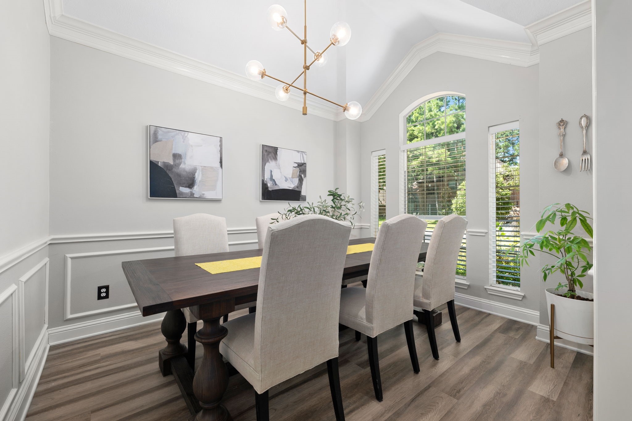 Elegant dining room featuring high ceilings, abundant natural light, and chic modern lighting.