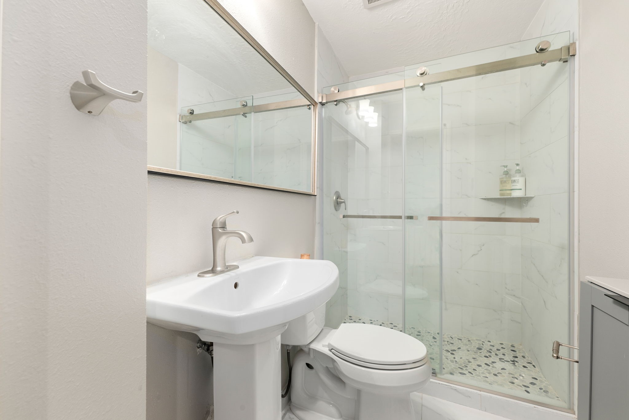 Modern bathroom featuring a sleek pedestal sink, elegant fixtures, and a spacious glass-enclosed shower with stylish tile work.