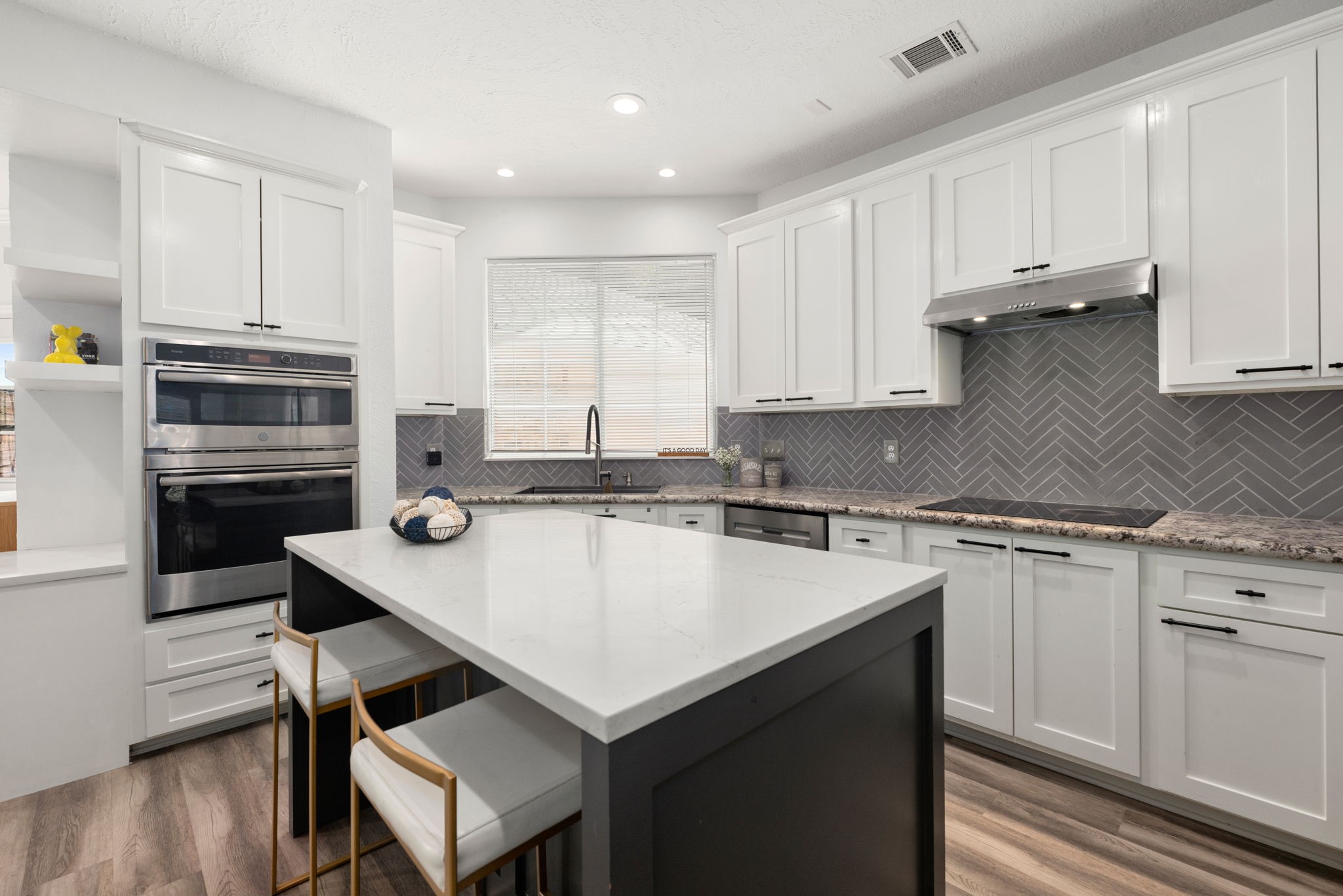 Modern kitchen featuring sleek white cabinetry, a stylish herringbone backsplash, and a spacious island with seating, perfect for culinary enthusiasts.